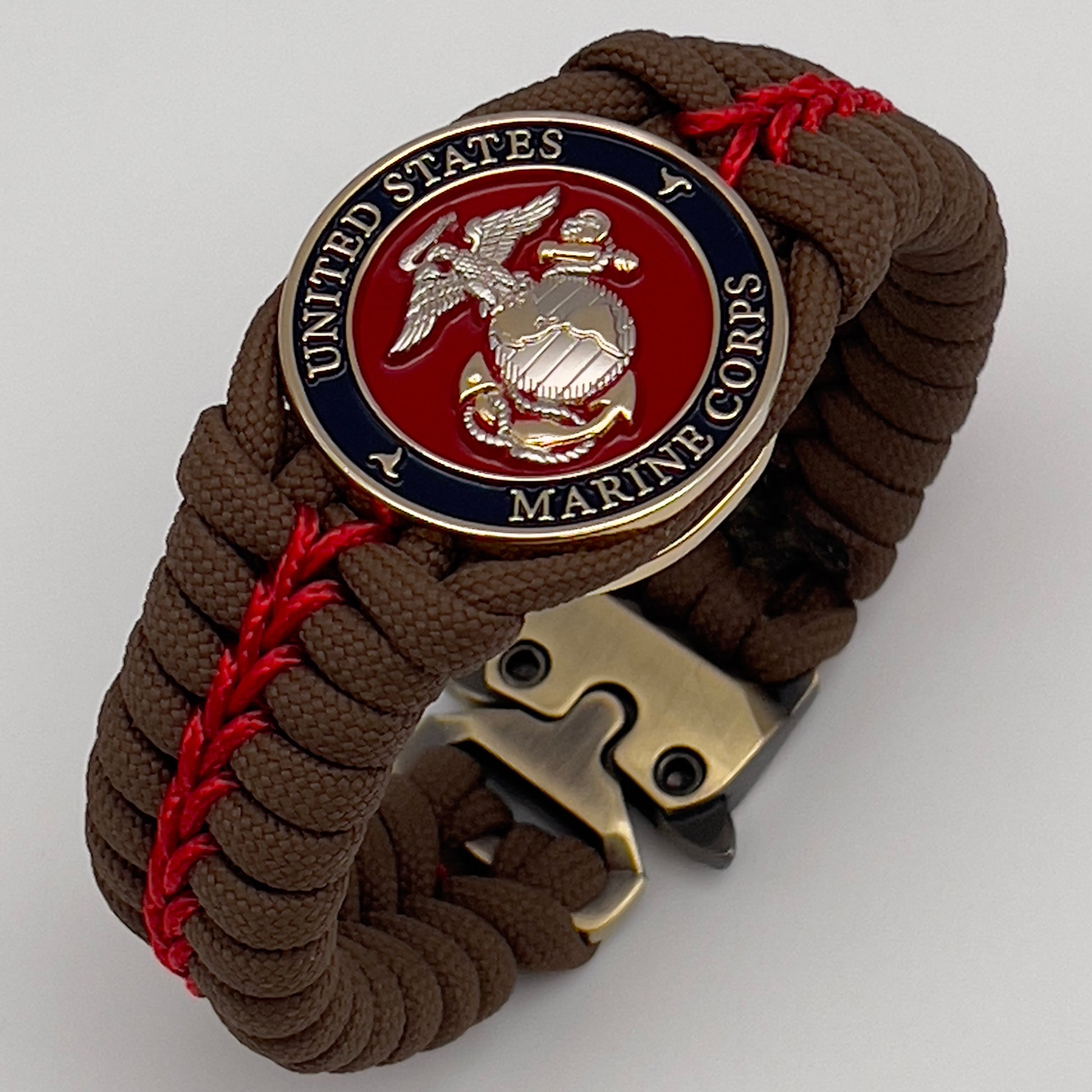 Thick, semi-rigid and comfortable braided United States Marine Corps bracelet featuring a 24K gold and silver plated USMC officer Eagle Globe and Anchor medallion, a Cobra style tactical buckle and woven with Coyote brown 550 and Imperial red micro paracord.