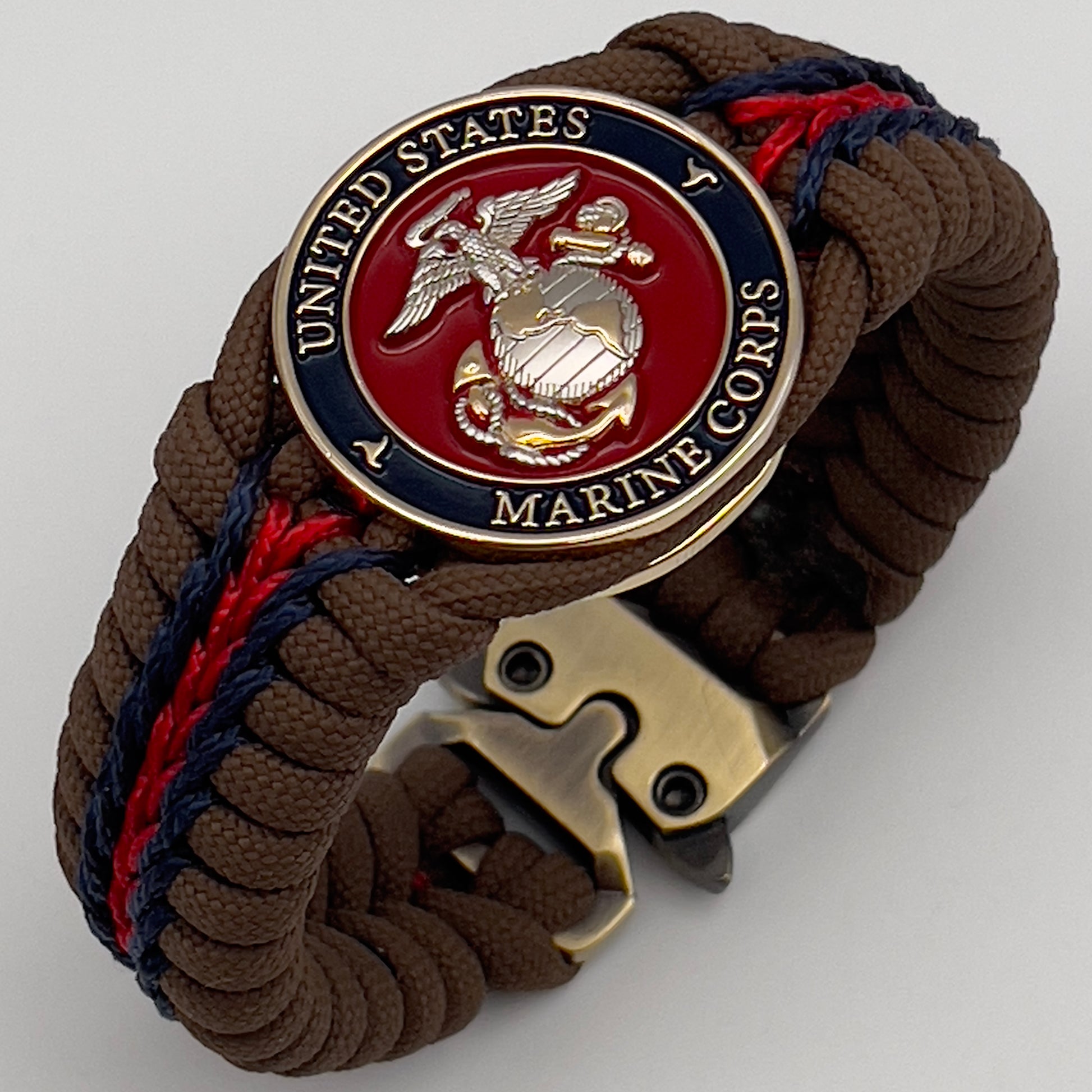Thick, semi-rigid and comfortable braided United States Marine Corps bracelet featuring a 24K gold and silver plated USMC officer Eagle Globe and Anchor medallion, a Cobra style tactical buckle and woven with Coyote brown 550, Navy blue and Imperial red micro paracord.