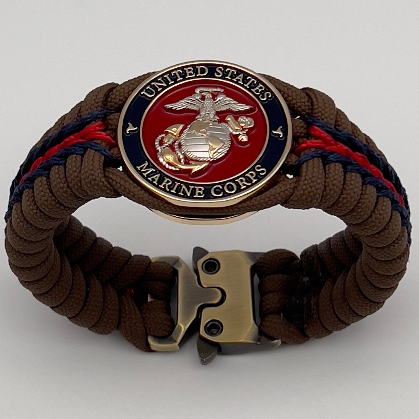 Thick, semi-rigid and comfortable braided United States Marine Corps bracelet featuring a 24K gold and silver plated USMC officer Eagle Globe and Anchor medallion, a Cobra style tactical buckle and woven with Coyote brown 550, Navy blue and Imperial red micro paracord.