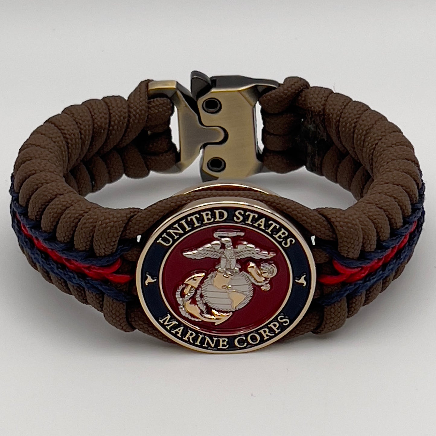 Thick, semi-rigid and comfortable braided United States Marine Corps bracelet featuring a 24K gold and silver plated USMC officer Eagle Globe and Anchor medallion, a Cobra style tactical buckle and woven with Coyote brown 550, Navy blue and Imperial red micro paracord.
