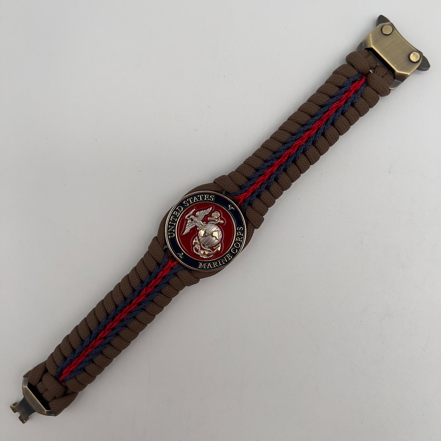 Thick, semi-rigid and comfortable braided United States Marine Corps bracelet featuring a 24K gold and silver plated USMC officer Eagle Globe and Anchor medallion, a Cobra style tactical buckle and woven with Coyote brown 550, Navy blue and Imperial red micro paracord.