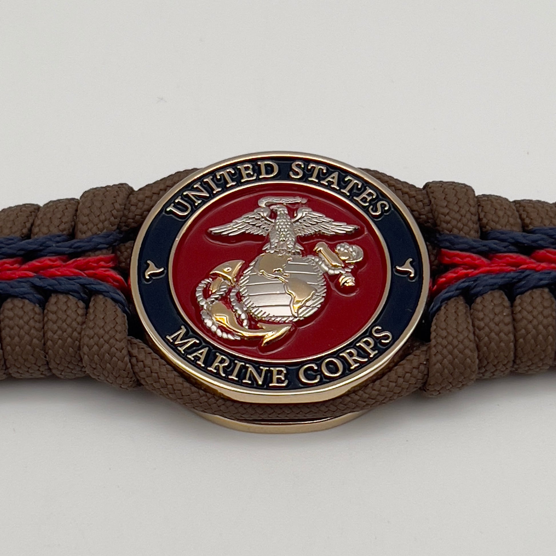 Thick, semi-rigid and comfortable braided United States Marine Corps bracelet featuring a 24K gold and silver plated USMC officer Eagle Globe and Anchor medallion, a Cobra style tactical buckle and woven with Coyote brown 550, Navy blue and Imperial red micro paracord.
