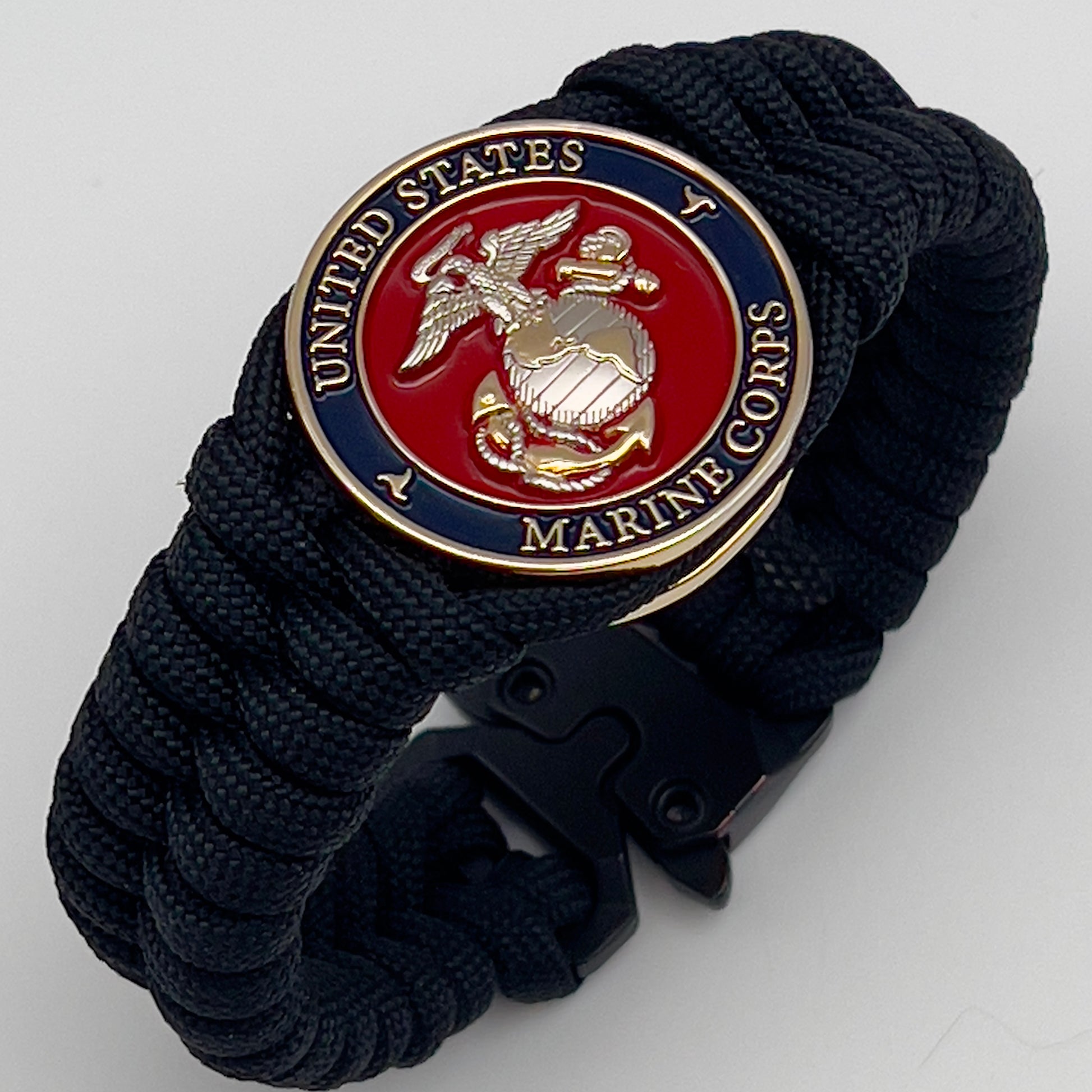 Thick, semi-rigid and comfortable braided United States Marine Corps bracelet featuring a 24K gold and silver plated USMC officer Eagle Globe and Anchor medallion, a black Cobra style tactical buckle and woven with black 550 paracord.