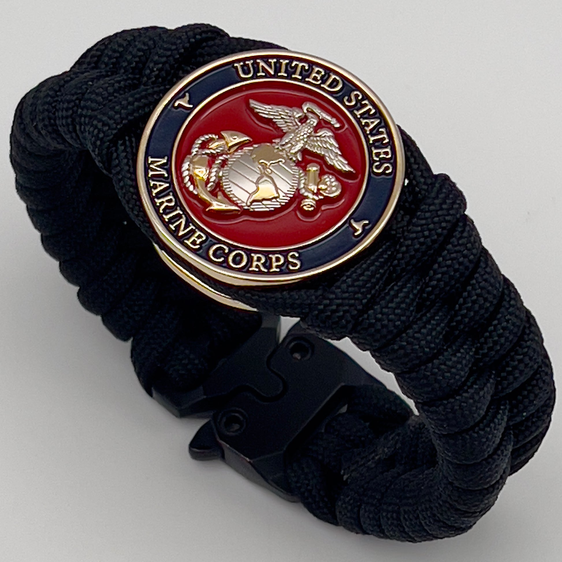 Thick, semi-rigid and comfortable braided United States Marine Corps bracelet featuring a 24K gold and silver plated USMC officer Eagle Globe and Anchor medallion, a black Cobra style tactical buckle and woven with black 550 paracord.