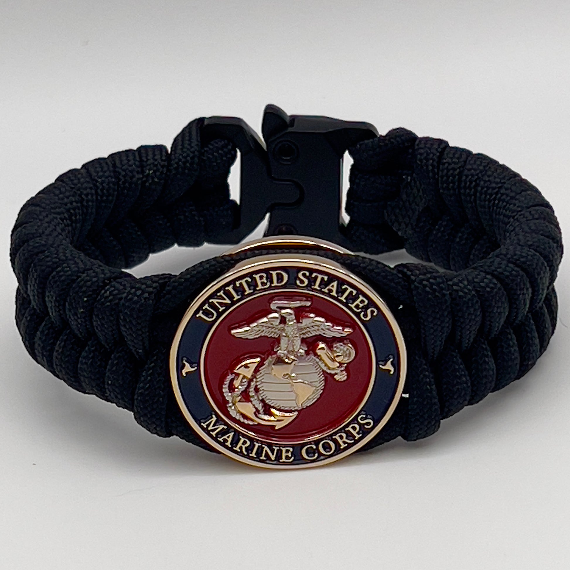 Thick, semi-rigid and comfortable braided United States Marine Corps bracelet featuring a 24K gold and silver plated USMC officer Eagle Globe and Anchor medallion, a black Cobra style tactical buckle and woven with black 550 paracord.