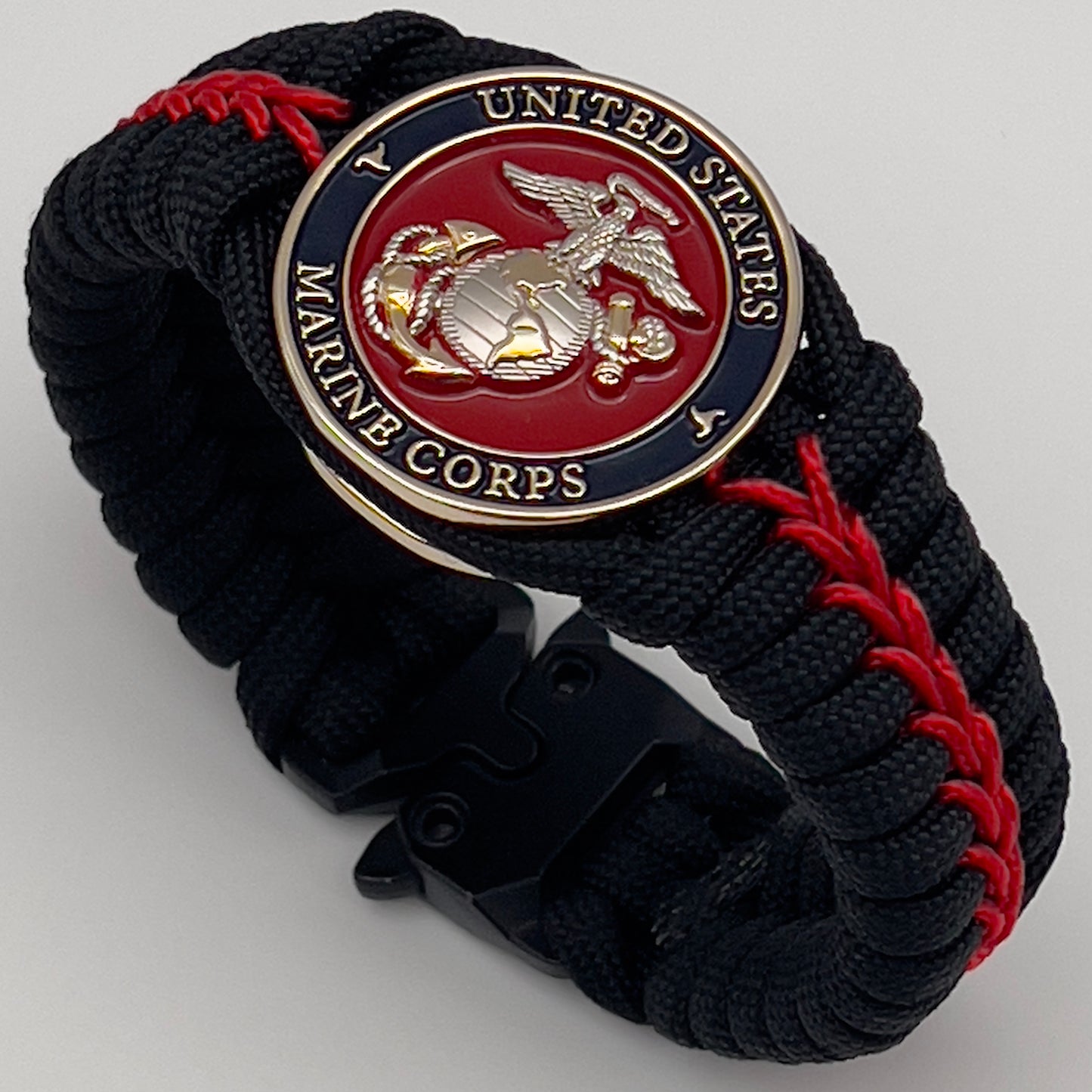 Thick, semi-rigid and comfortable braided United States Marine Corps bracelet featuring a 24K gold and silver plated USMC officer Eagle Globe and Anchor medallion, a black Cobra style tactical buckle and woven with black 550 and Imperial red micro paracord.