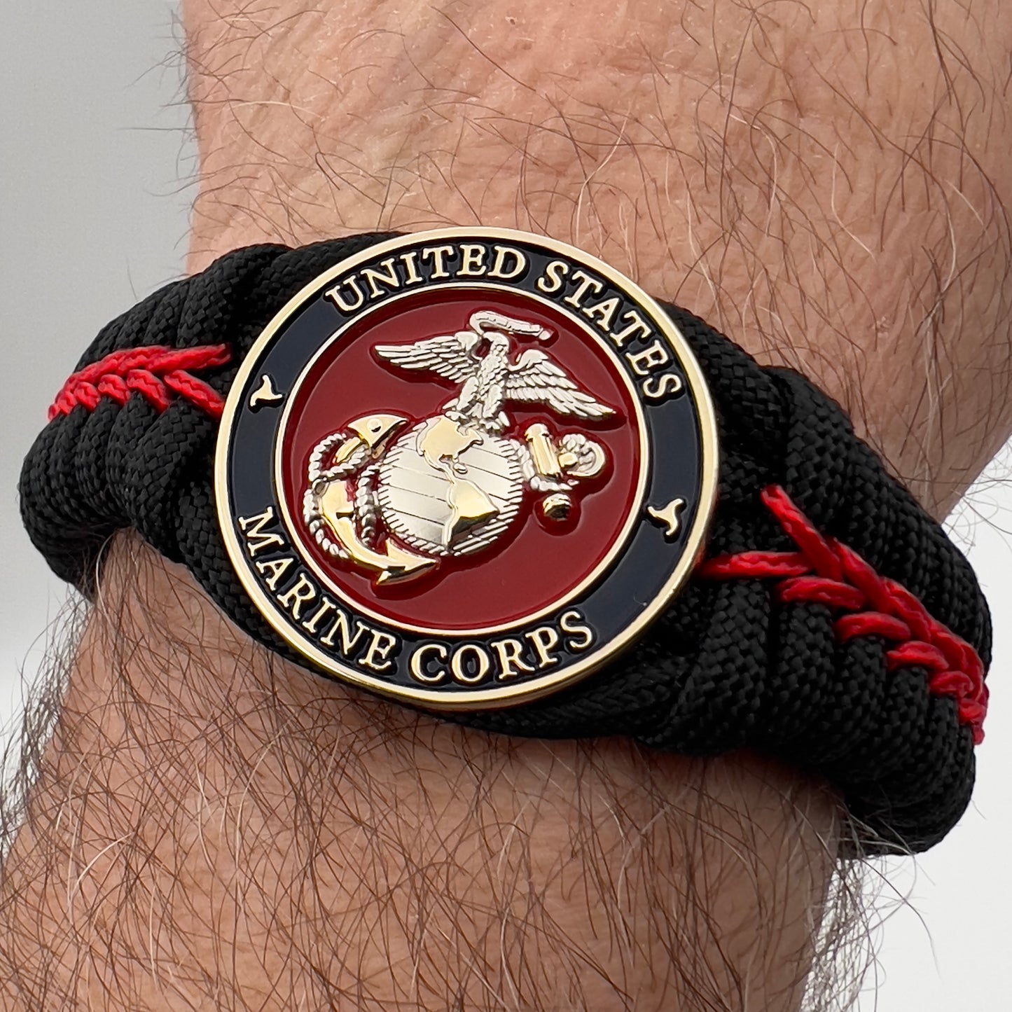 Thick, semi-rigid and comfortable braided United States Marine Corps bracelet featuring a 24K gold and silver plated USMC officer Eagle Globe and Anchor medallion, a black Cobra style tactical buckle and woven with black 550 and Imperial red micro paracord.