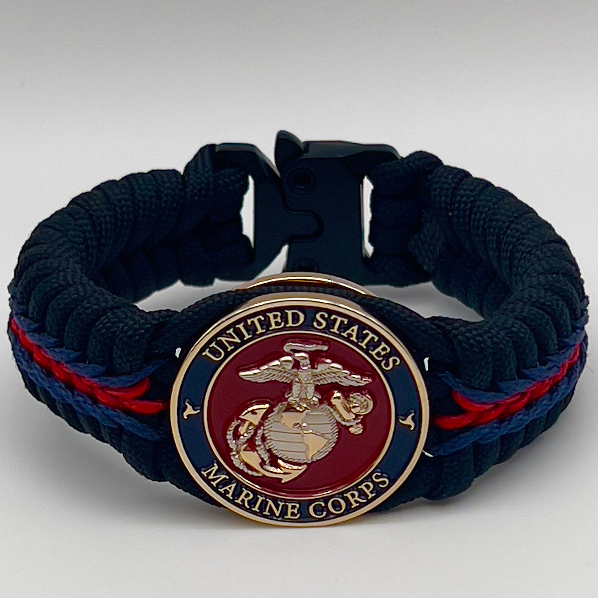 Thick, semi-rigid and comfortable braided United States Marine Corps bracelet featuring a 24K gold and silver plated USMC officer Eagle Globe and Anchor medallion, a black Cobra style tactical buckle and woven with Navy blue, Imperial red and black paracord.