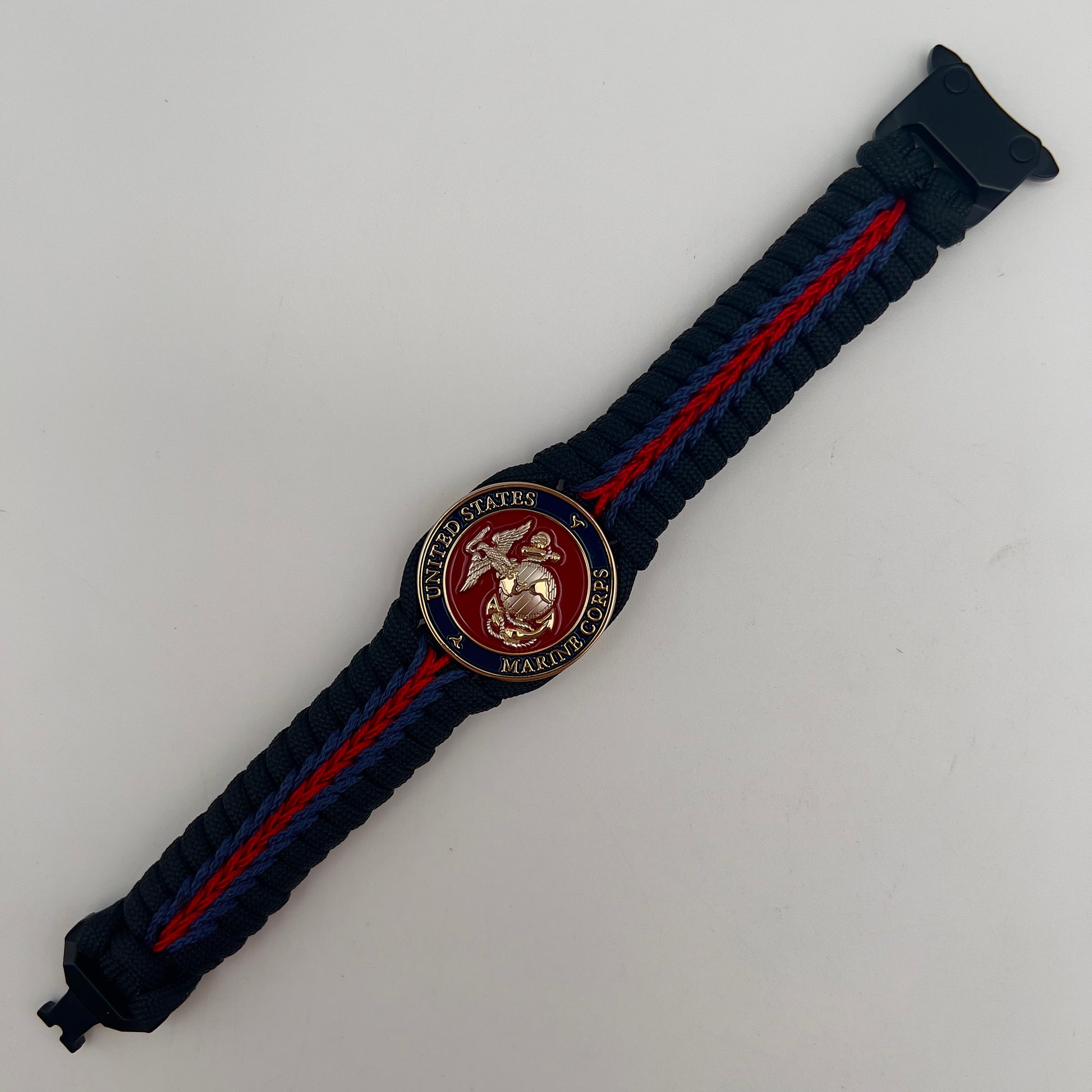Thick, semi-rigid and comfortable braided United States Marine Corps bracelet featuring a 24K gold and silver plated USMC officer Eagle Globe and Anchor medallion, a black Cobra style tactical buckle and woven with Navy blue, Imperial red and black paracord.