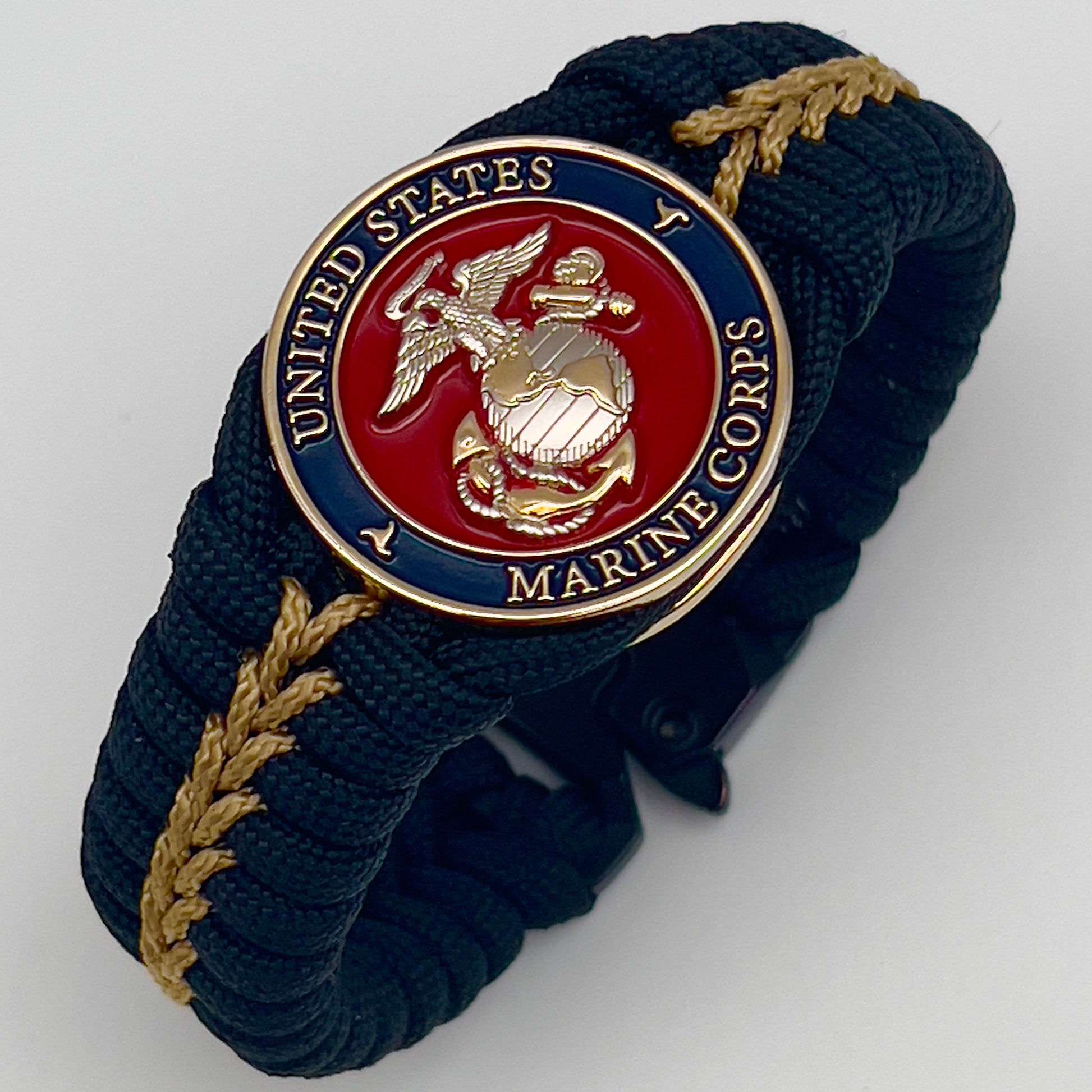 Thick, semi-rigid and comfortable braided United States Marine Corps bracelet featuring a 24K gold and silver plated USMC officer Eagle Globe and Anchor medallion, a black Cobra style tactical buckle and woven with black 550 and gold micro paracord.