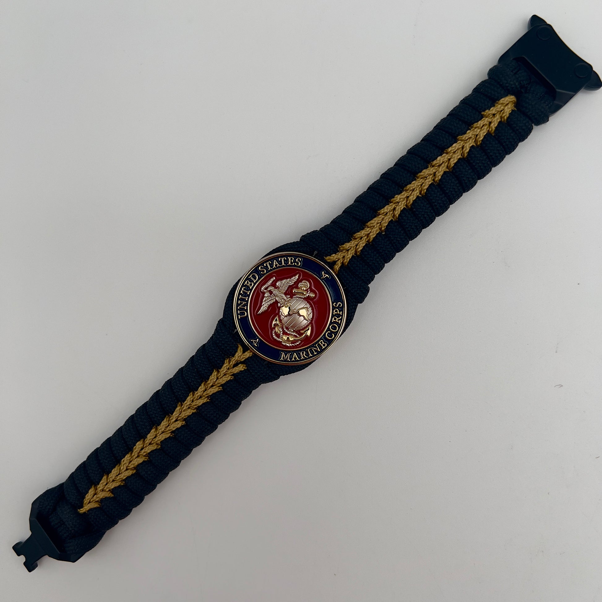 Thick, semi-rigid and comfortable braided United States Marine Corps bracelet featuring a 24K gold and silver plated USMC officer Eagle Globe and Anchor medallion, a black Cobra style tactical buckle and woven with black 550 and gold micro paracord.