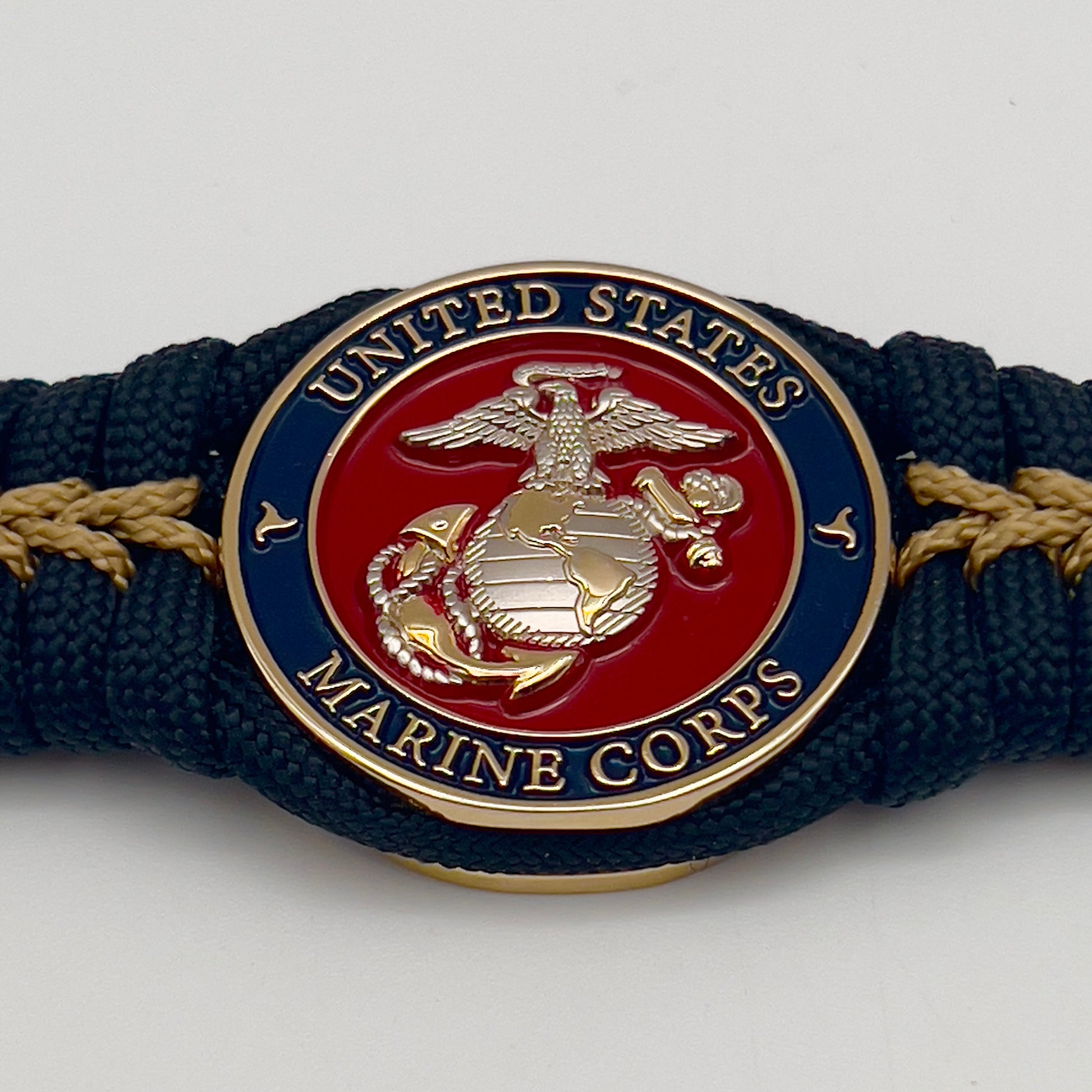 Thick, semi-rigid and comfortable braided United States Marine Corps bracelet featuring a 24K gold and silver plated USMC officer Eagle Globe and Anchor medallion, a black Cobra style tactical buckle and woven with black 550 and gold micro paracord.