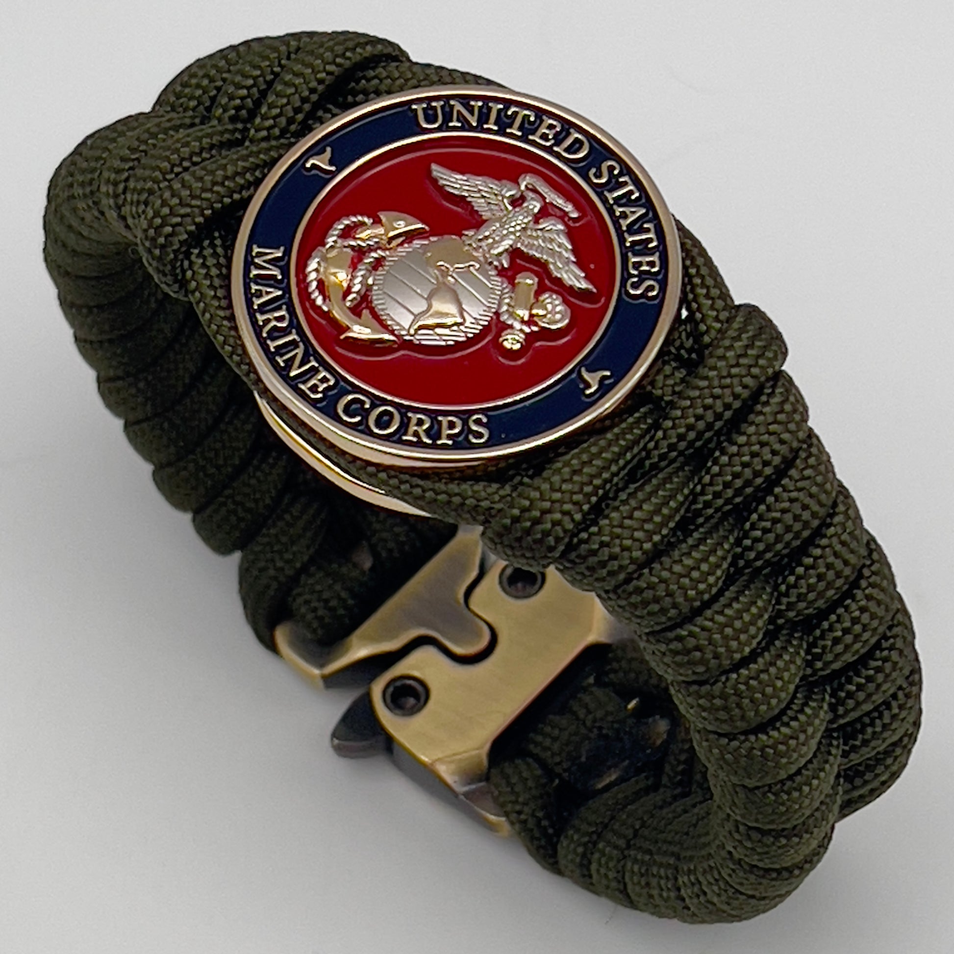 Thick, semi-rigid and comfortable braided United States Marine Corps bracelet featuring a 24K gold and silver plated USMC officer Eagle Globe and Anchor medallion, a gold Cobra style tactical buckle and woven with olive drab 550 paracord.