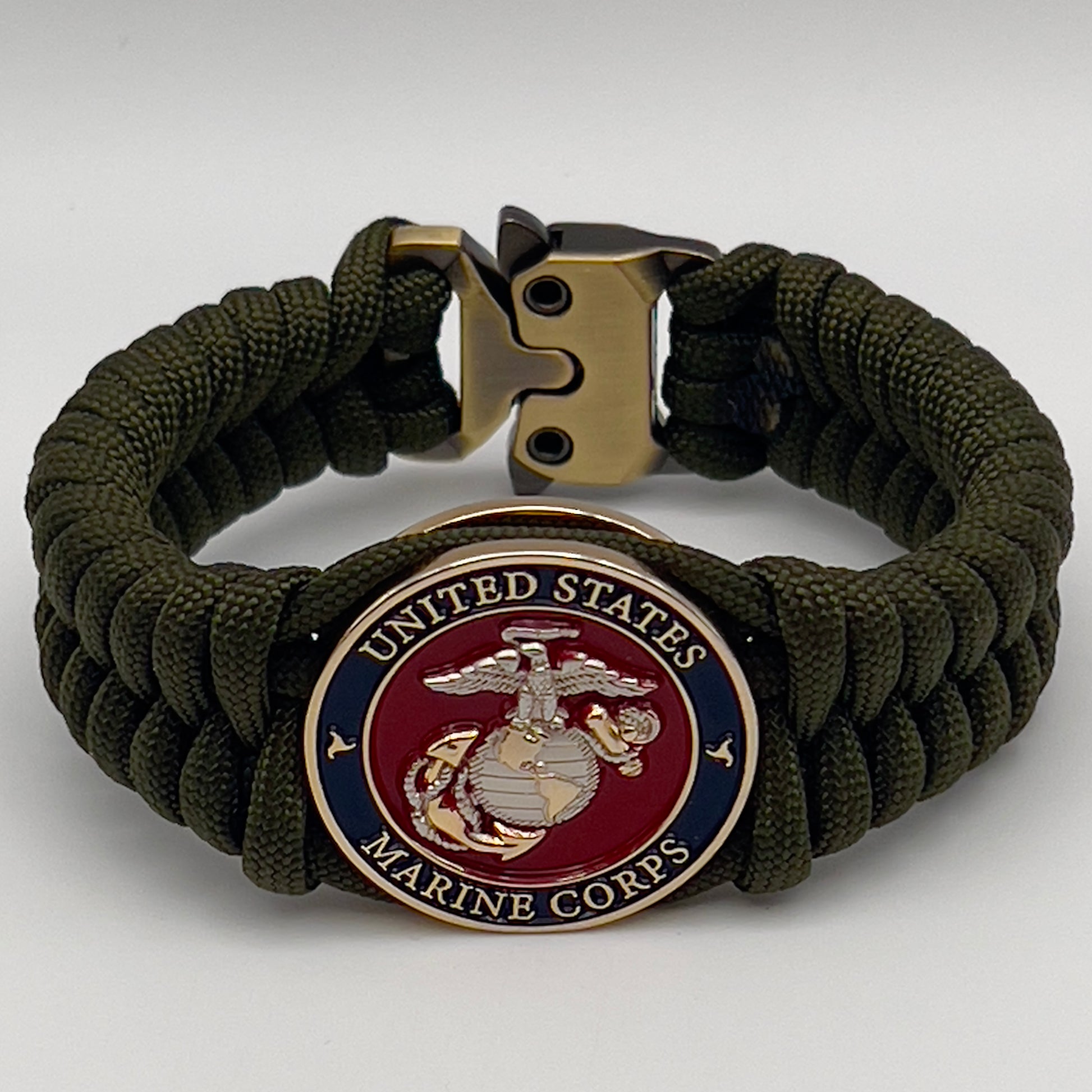 Thick, semi-rigid and comfortable braided United States Marine Corps bracelet featuring a 24K gold and silver plated USMC officer Eagle Globe and Anchor medallion, a gold Cobra style tactical buckle and woven with olive drab 550 paracord.