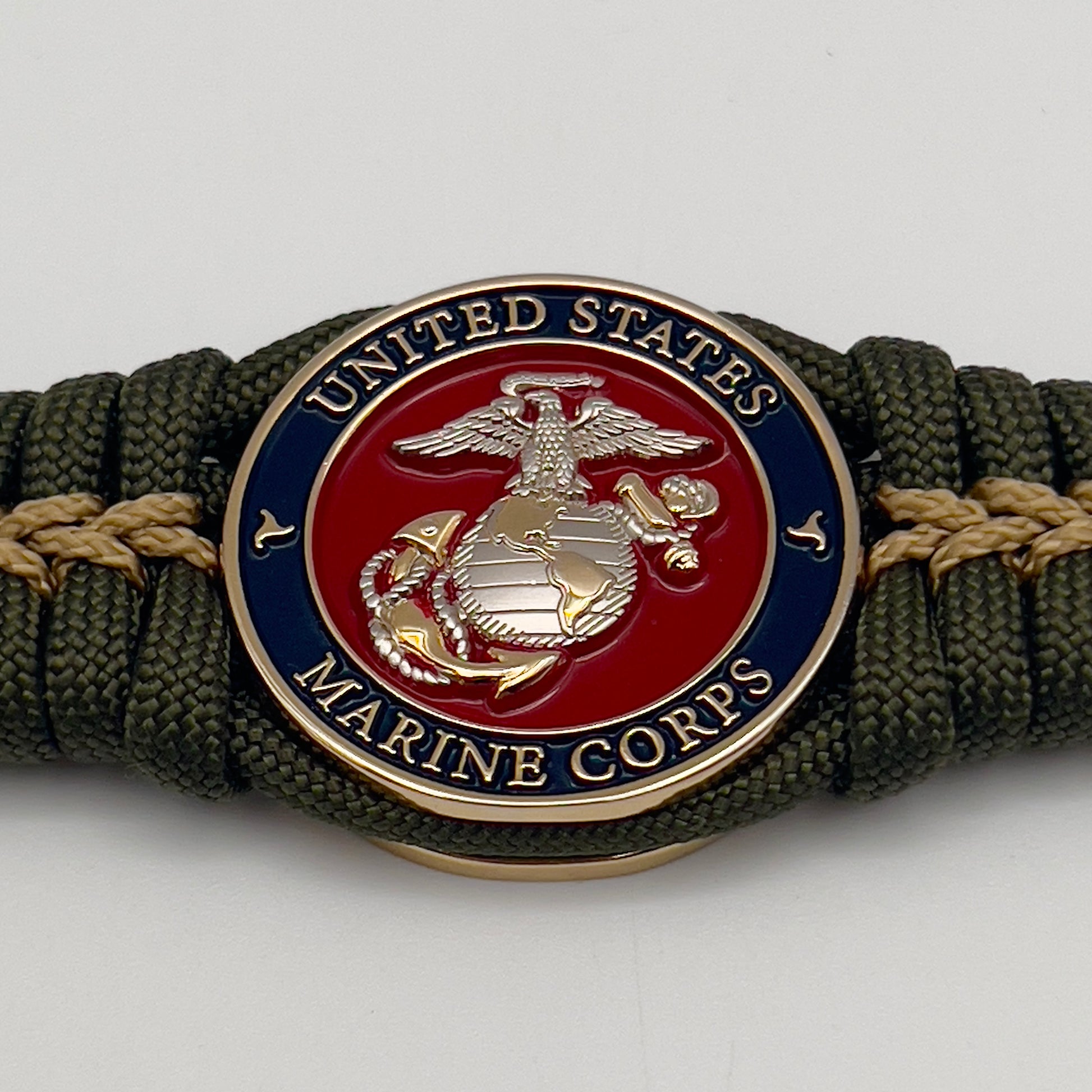 Thick, semi-rigid and comfortable braided United States Marine Corps bracelet featuring a 24K gold and silver plated USMC officer Eagle Globe and Anchor medallion, a gold Cobra style tactical buckle and woven with olive drab 550 and gold micro paracord.
