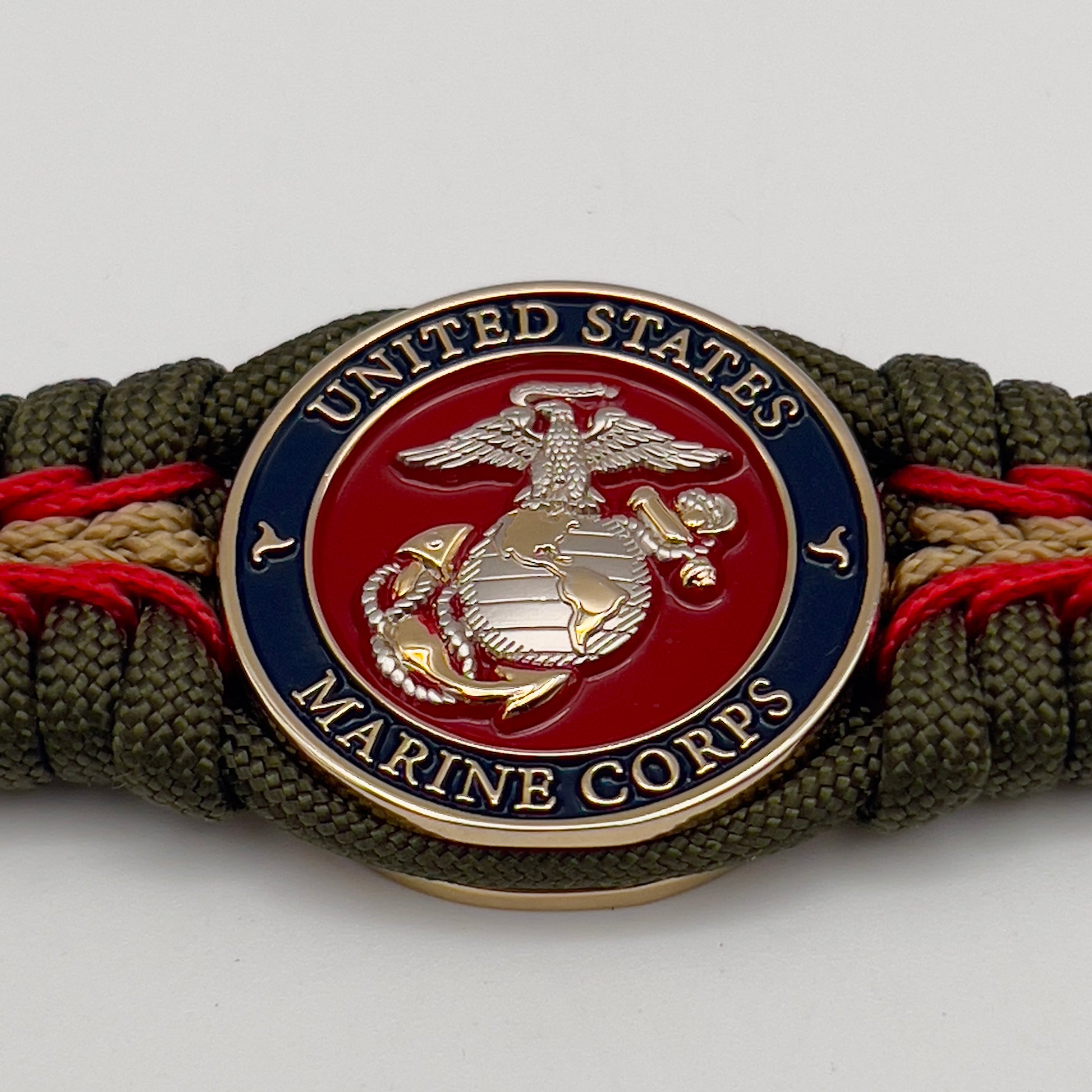 Thick, semi-rigid and comfortable braided United States Marine Corps bracelet featuring a 24K gold and silver plated USMC officer Eagle Globe and Anchor medallion, a gold Cobra style tactical buckle and woven with olive drab 550 and gold micro paracord.