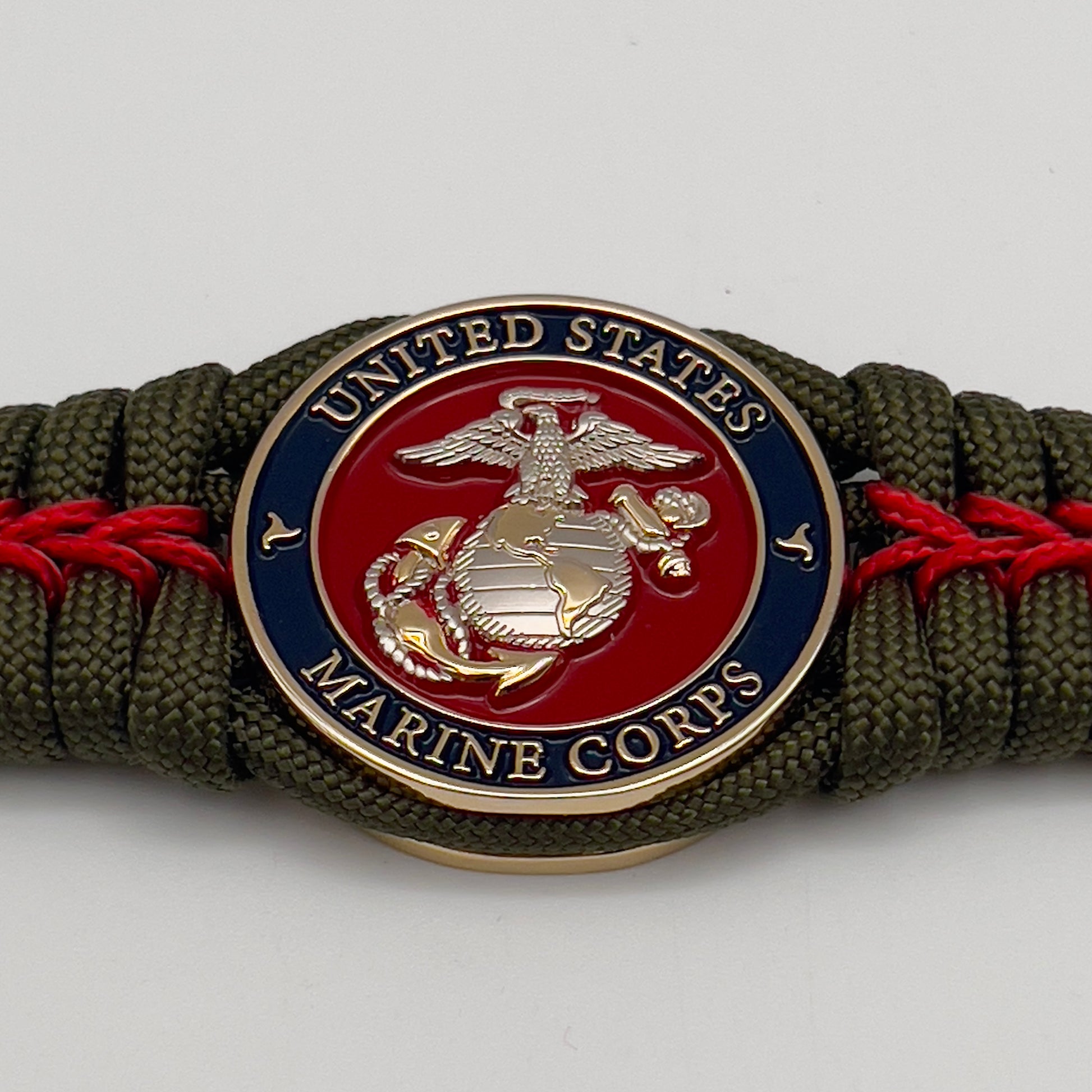 Thick, semi-rigid and comfortable braided United States Marine Corps bracelet featuring a 24K gold and silver plated USMC officer Eagle Globe and Anchor medallion, a gold Cobra style tactical buckle and woven with olive drab 550 and Imperial red micro paracord.