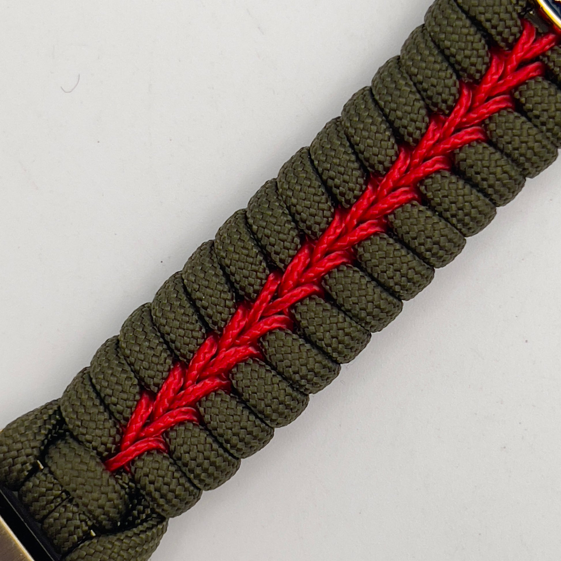 Thick, semi-rigid and comfortable braided United States Marine Corps bracelet featuring a 24K gold and silver plated USMC officer Eagle Globe and Anchor medallion, a gold Cobra style tactical buckle and woven with olive drab 550 and Imperial red micro paracord.