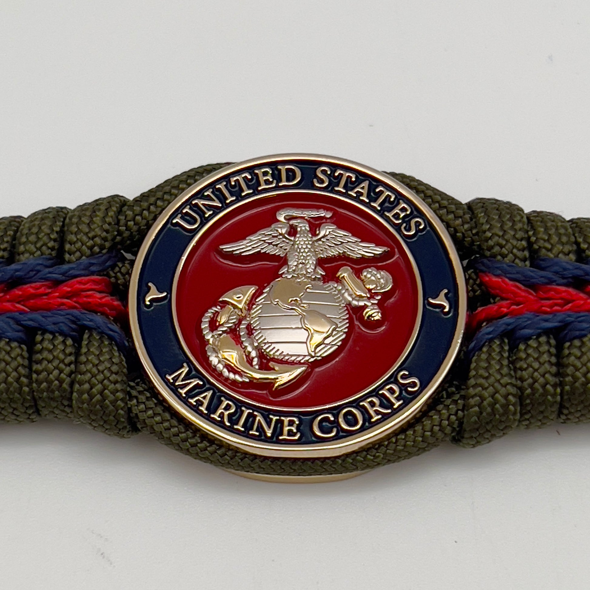 Thick, semi-rigid and comfortable braided United States Marine Corps bracelet featuring a 24K gold and silver plated USMC officer Eagle Globe and Anchor medallion, a gold Cobra style tactical buckle and woven with olive drab 550 and Imperial red and gold micro paracord.