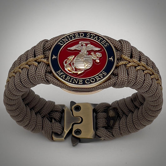 Thick, semi-rigid and comfortable braided United States Marine Corps bracelet featuring a 24K gold and silver plated USMC officer Eagle Globe and Anchor medallion, a gold Cobra style tactical buckle and woven with tan 550 paracord and gold micro cord.