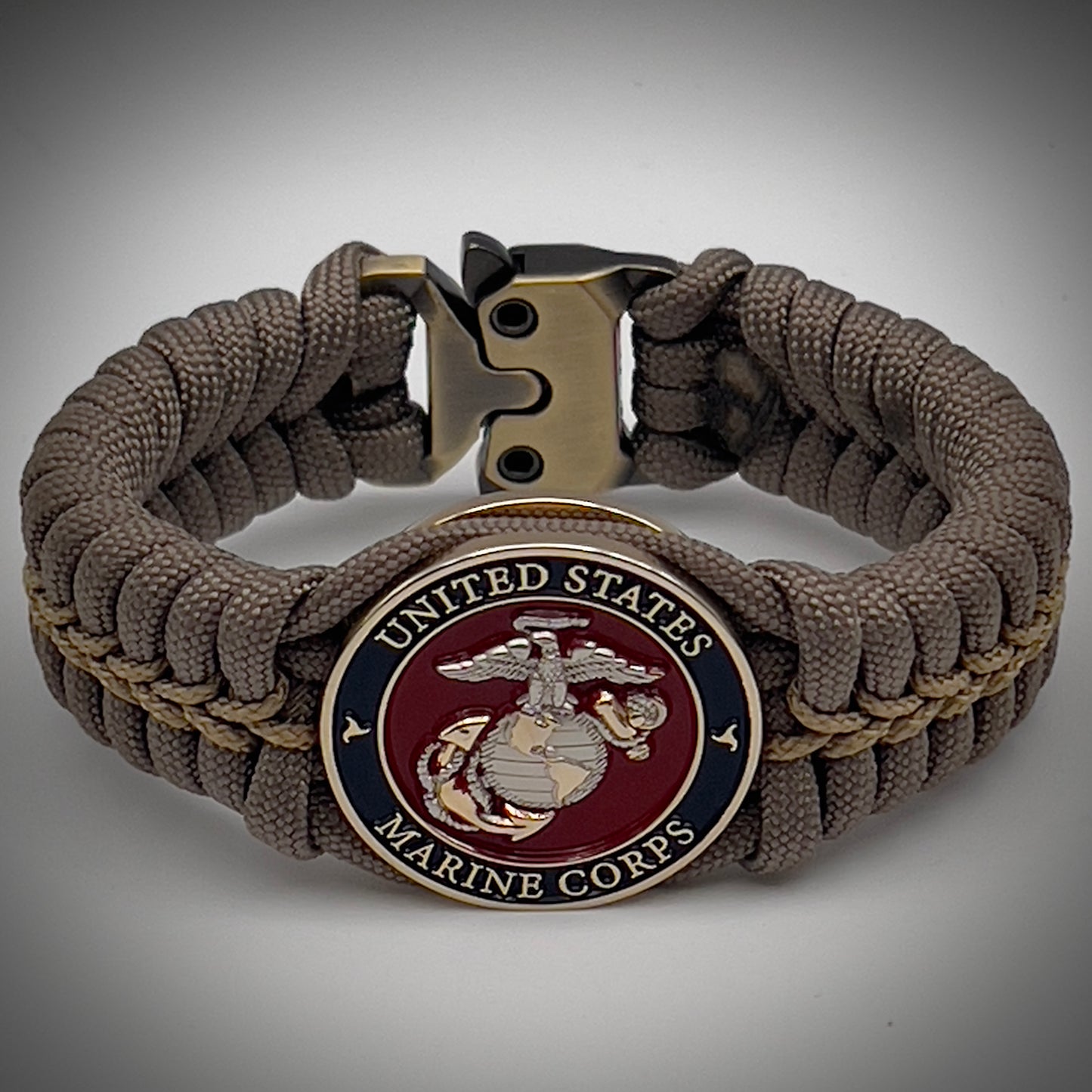 Thick, semi-rigid and comfortable braided United States Marine Corps bracelet featuring a 24K gold and silver plated USMC officer Eagle Globe and Anchor medallion, a gold Cobra style tactical buckle and woven with tan 550 paracord and gold micro cord.