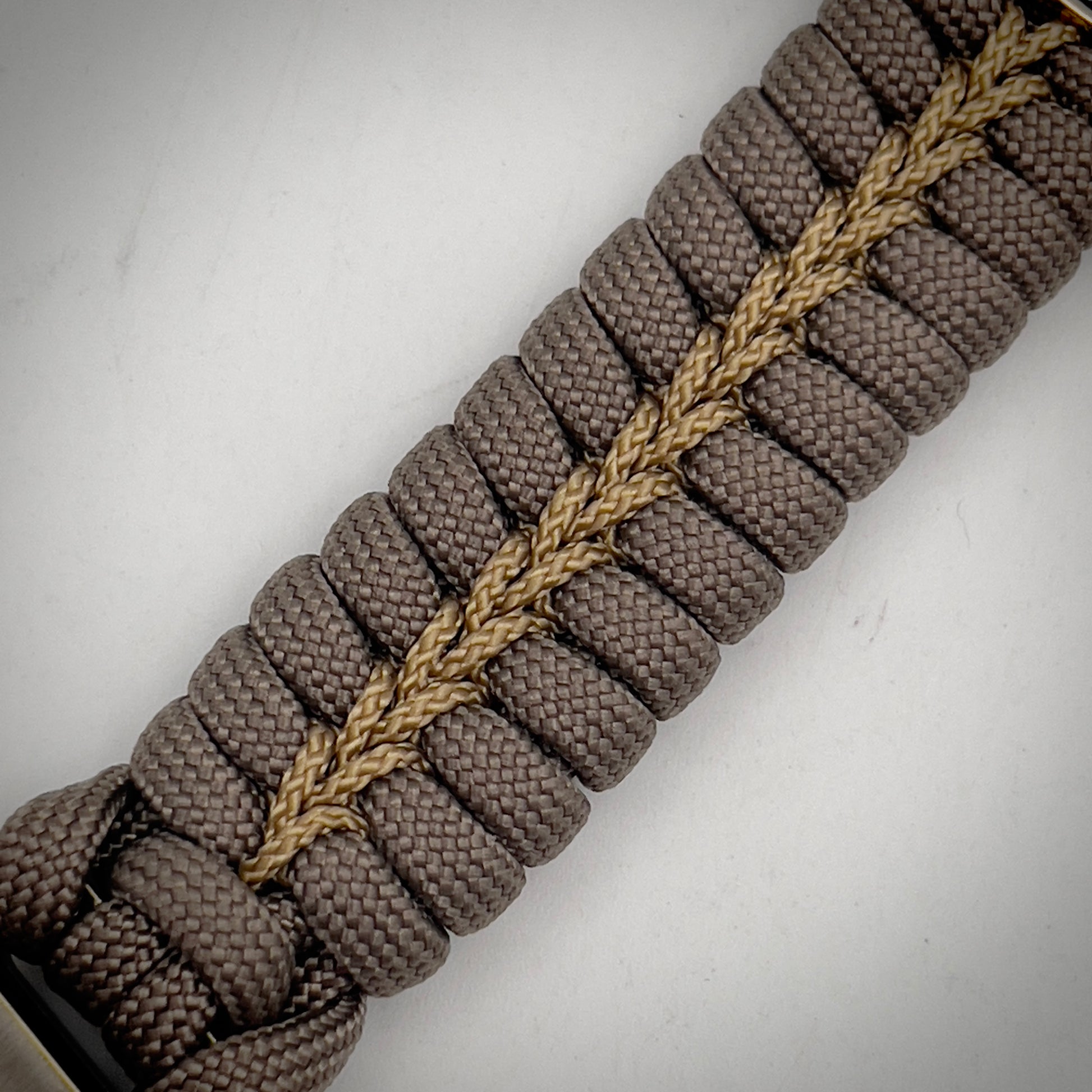 Thick, semi-rigid and comfortable braided United States Marine Corps bracelet featuring a 24K gold and silver plated USMC officer Eagle Globe and Anchor medallion, a gold Cobra style tactical buckle and woven with tan 550 paracord and gold micro cord.
