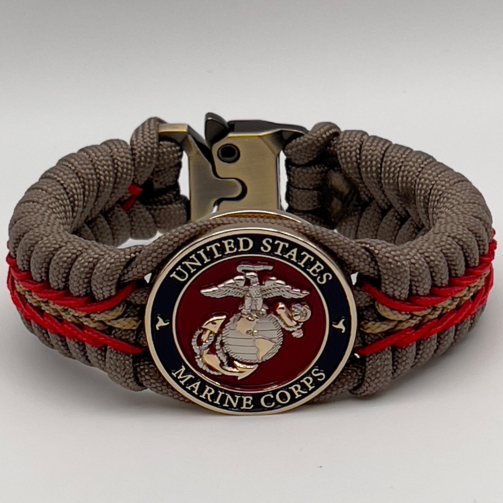 Thick and comfortable braided United States Marine Corps bracelet featuring a 24K gold and silver plated USMC officer Eagle Globe and Anchor medallion, a Cobra style tactical buckle and woven with tan 550, Imperial red and gold micro paracord.