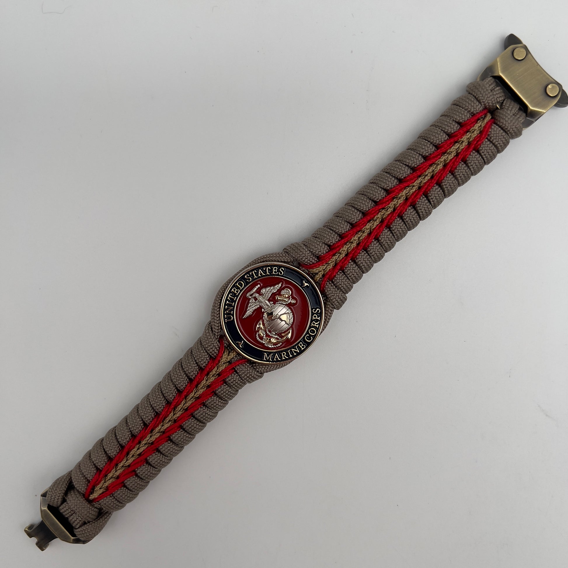 Thick and comfortable braided United States Marine Corps bracelet featuring a 24K gold and silver plated USMC officer Eagle Globe and Anchor medallion, a Cobra style tactical buckle and woven with tan 550, Imperial red and gold micro paracord.