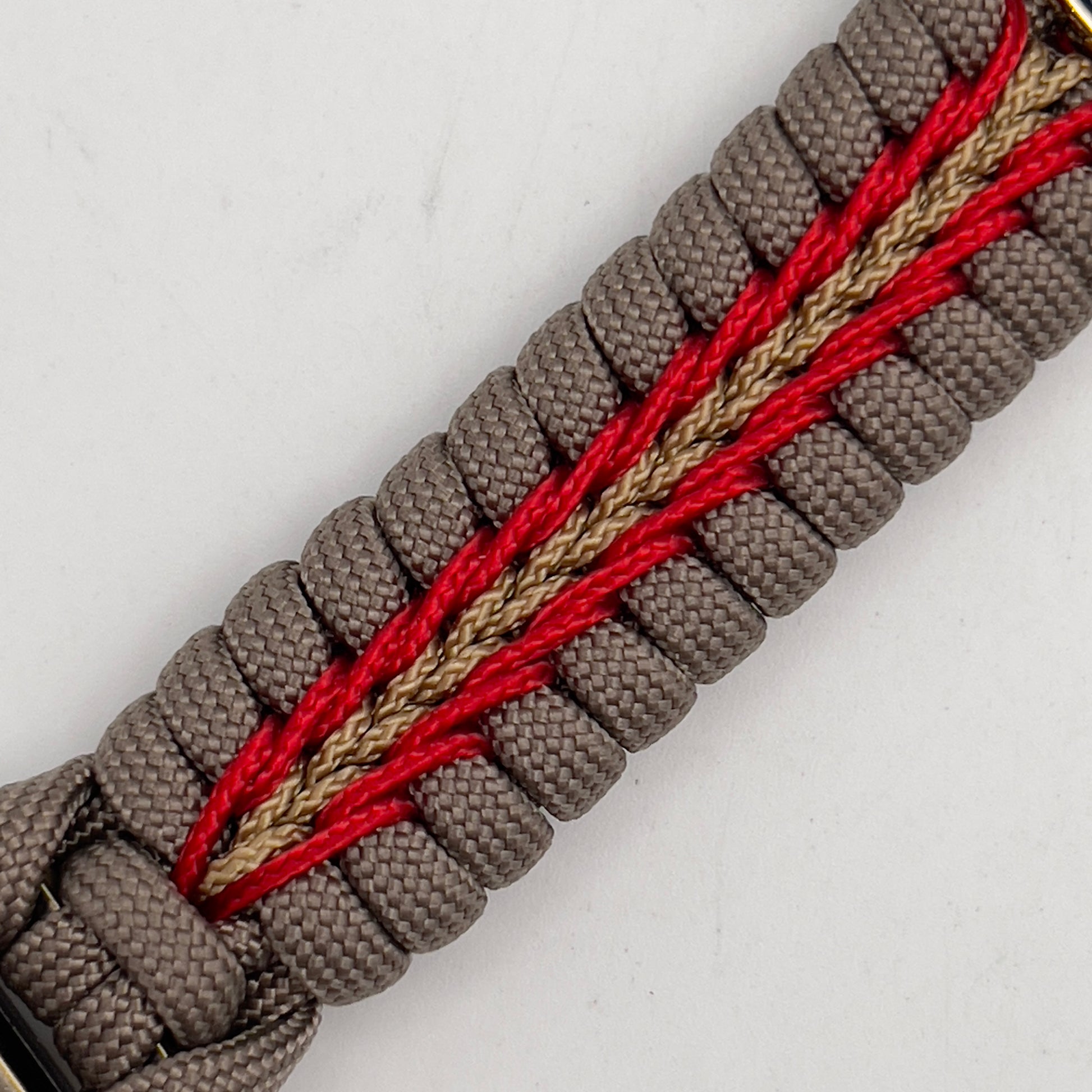 Thick and comfortable braided United States Marine Corps bracelet featuring a 24K gold and silver plated USMC officer Eagle Globe and Anchor medallion, a Cobra style tactical buckle and woven with tan 550, Imperial red and gold micro paracord.