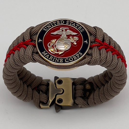 Thick, semi-rigid and comfortable braided United States Marine Corps bracelet featuring a 24K gold and silver plated USMC officer Eagle Globe and Anchor medallion, a gold Cobra style tactical buckle and woven with tan 550 paracord and Imperial red micro cord.