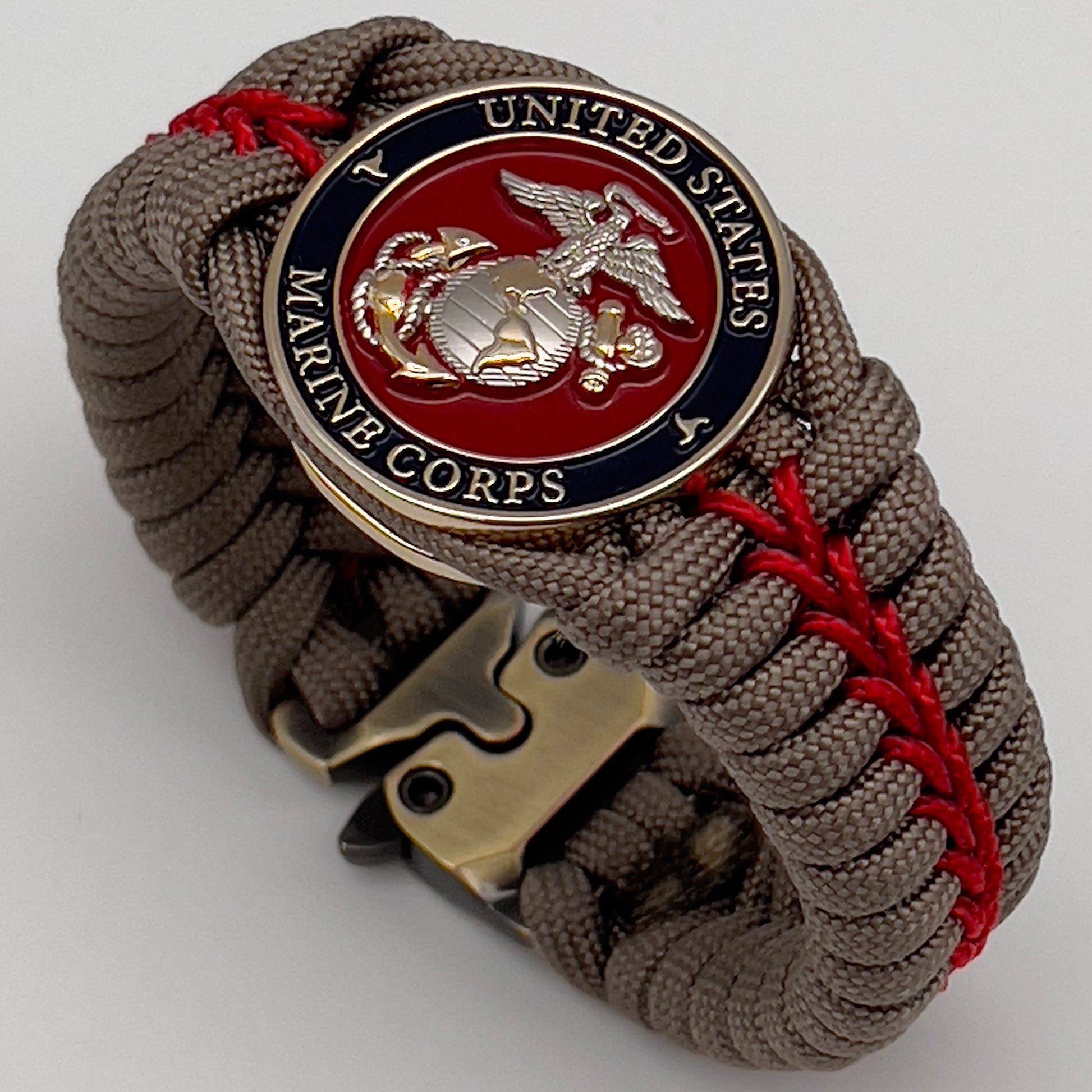 Thick, semi-rigid and comfortable braided United States Marine Corps bracelet featuring a 24K gold and silver plated USMC officer Eagle Globe and Anchor medallion, a gold Cobra style tactical buckle and woven with tan 550 paracord and Imperial red micro cord.