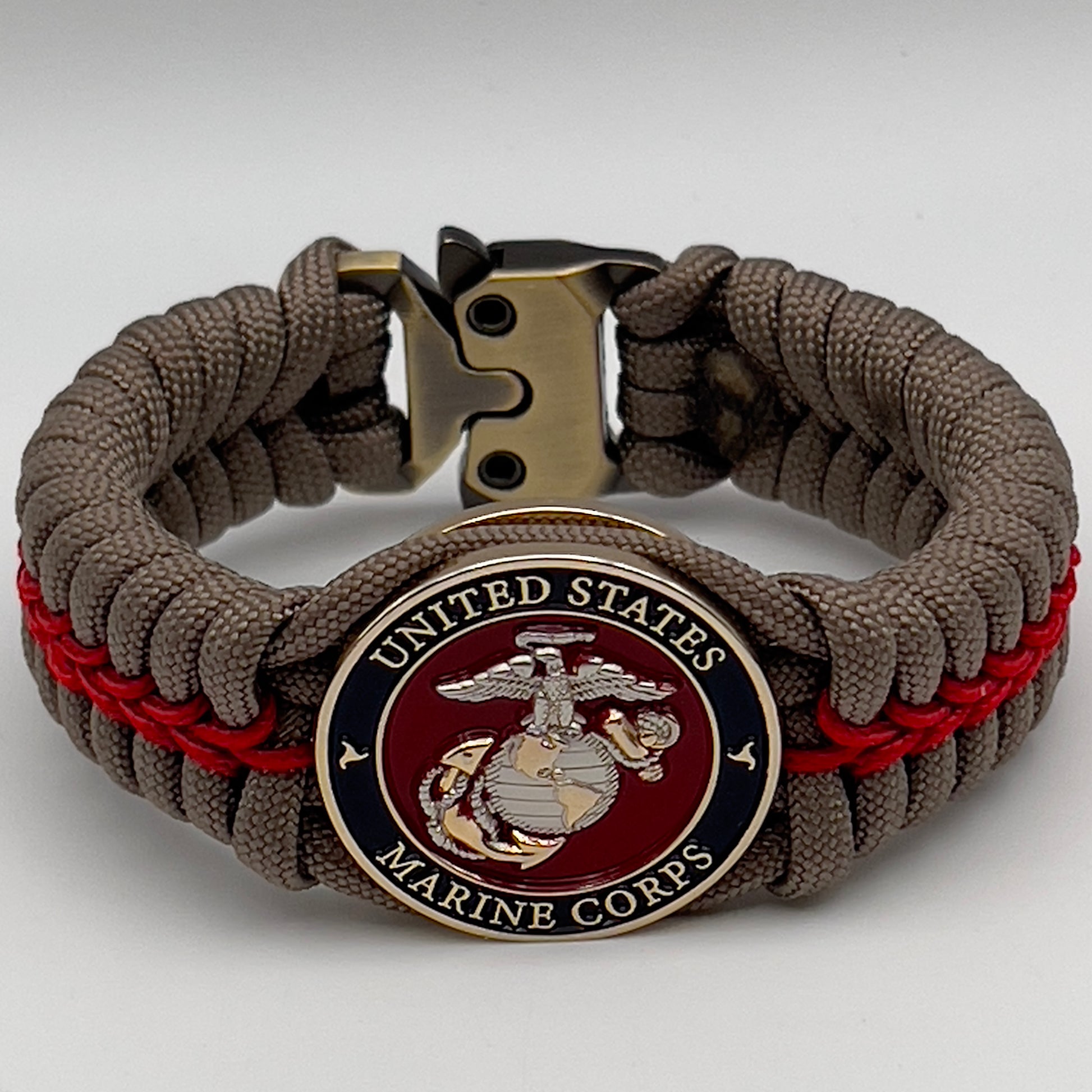 Thick, semi-rigid and comfortable braided United States Marine Corps bracelet featuring a 24K gold and silver plated USMC officer Eagle Globe and Anchor medallion, a gold Cobra style tactical buckle and woven with tan 550 paracord and Imperial red micro cord.