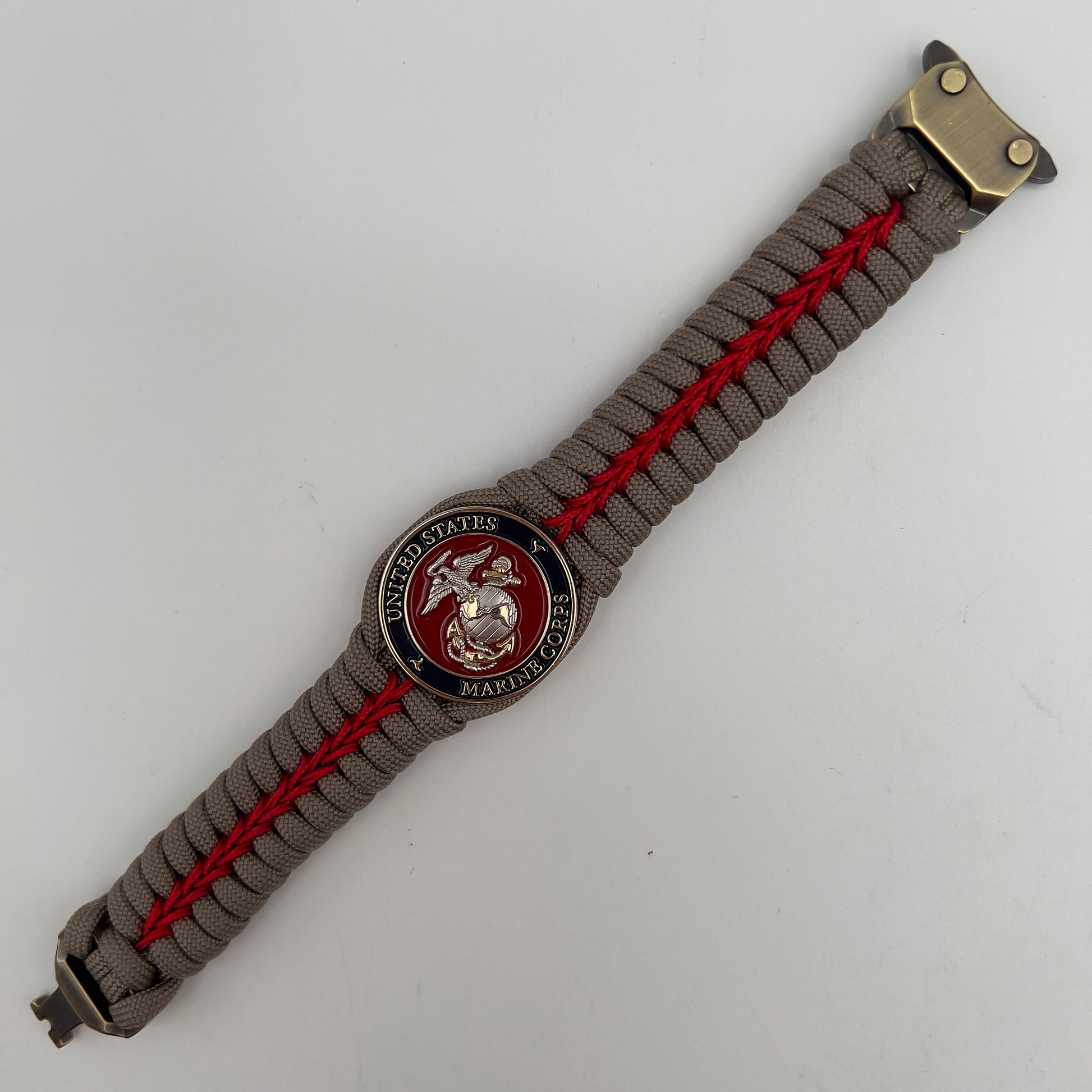 Thick, semi-rigid and comfortable braided United States Marine Corps bracelet featuring a 24K gold and silver plated USMC officer Eagle Globe and Anchor medallion, a gold Cobra style tactical buckle and woven with tan 550 paracord and Imperial red micro cord.