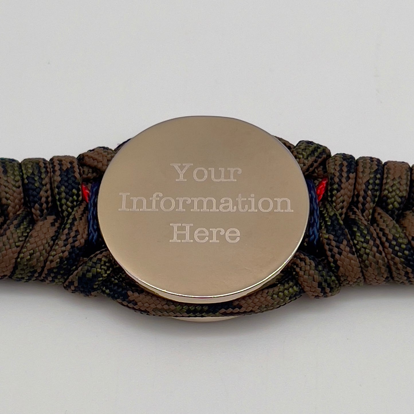 Thick, semi-rigid and comfortable braided United States Marine Corps bracelet featuring a 24K gold and silver plated USMC officer Eagle Globe and Anchor medallion, a gold Cobra style tactical buckle and woven with Woodland Camo 550 paracord and Imperial Red and Navy Blue micro cord.