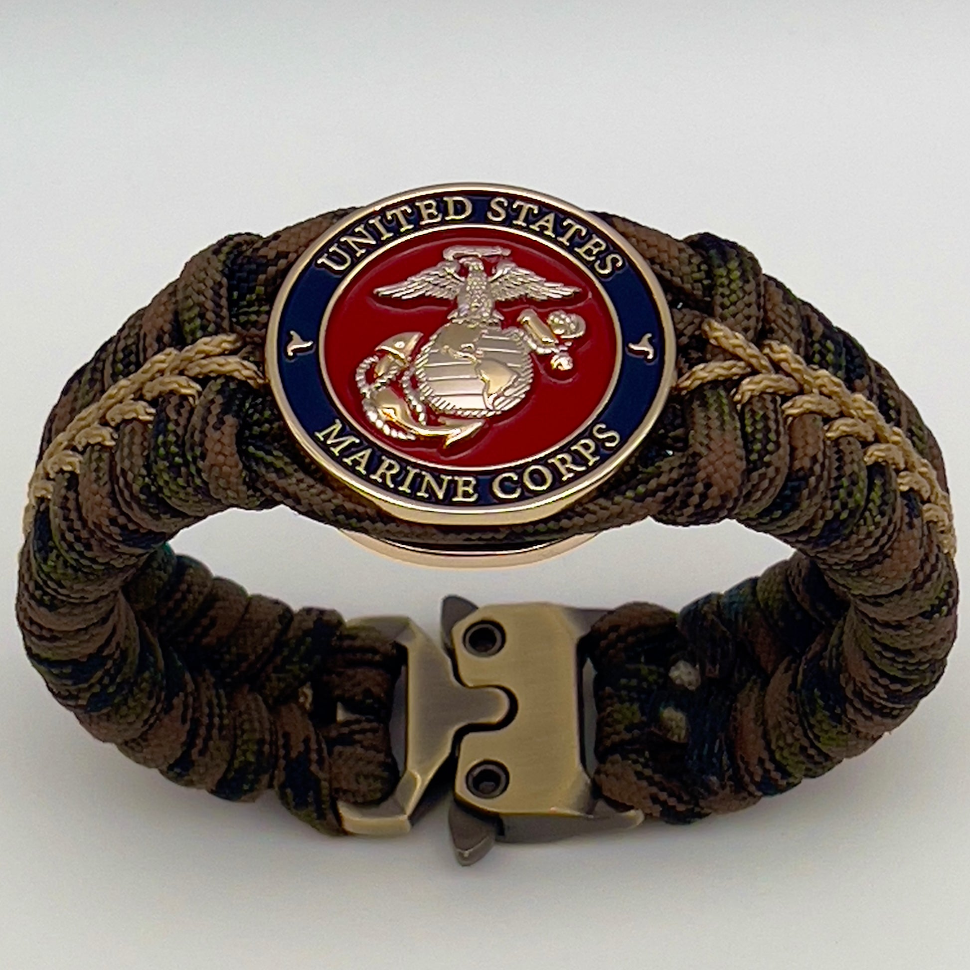 Thick, semi-rigid and comfortable braided United States Marine Corps bracelet featuring a 24K gold and silver plated USMC officer Eagle Globe and Anchor medallion, a gold Cobra style tactical buckle and woven with Woodland Camo 550 paracord and gold micro cord.