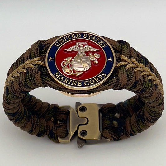 Thick, semi-rigid and comfortable braided United States Marine Corps bracelet featuring a 24K gold and silver plated USMC officer Eagle Globe and Anchor medallion, a gold Cobra style tactical buckle and woven with Woodland Camo 550 paracord and gold micro cord.