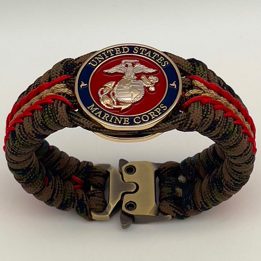 Thick, semi-rigid and comfortable braided United States Marine Corps bracelet featuring a 24K gold and silver plated USMC officer Eagle Globe and Anchor medallion, a gold Cobra style tactical buckle and woven with Woodland Camo 550 paracord and Imperial Red and gold micro cord.