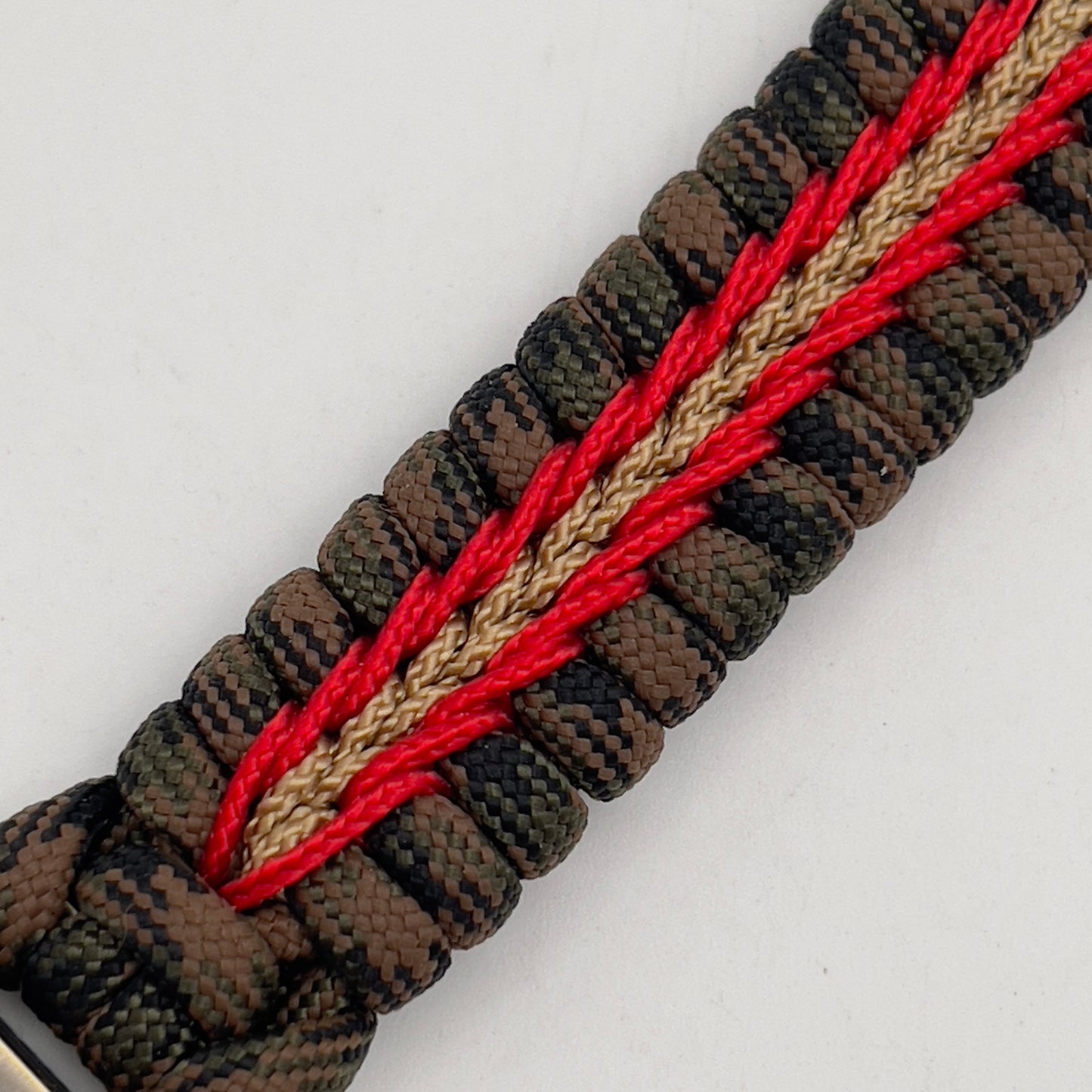 Thick, semi-rigid and comfortable braided United States Marine Corps bracelet featuring a 24K gold and silver plated USMC officer Eagle Globe and Anchor medallion, a gold Cobra style tactical buckle and woven with Woodland Camo 550 paracord and Imperial Red and gold micro cord.