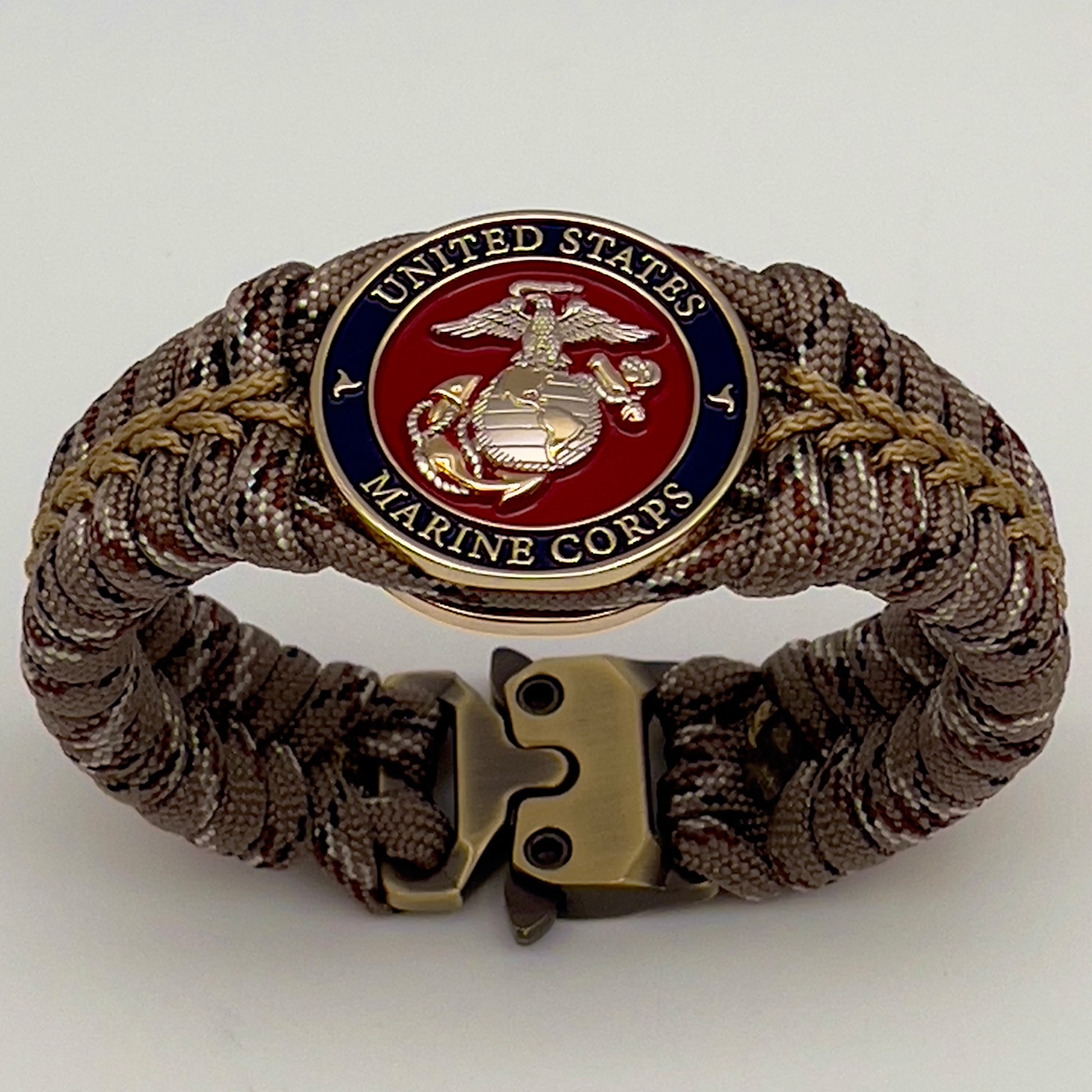 Thick and comfortable braided United States Marine Corps bracelet featuring a 24K gold and silver plated USMC officer Eagle Globe and Anchor medallion, a Cobra style tactical buckle and woven with Desert Camo 550 paracord gold micro cord.