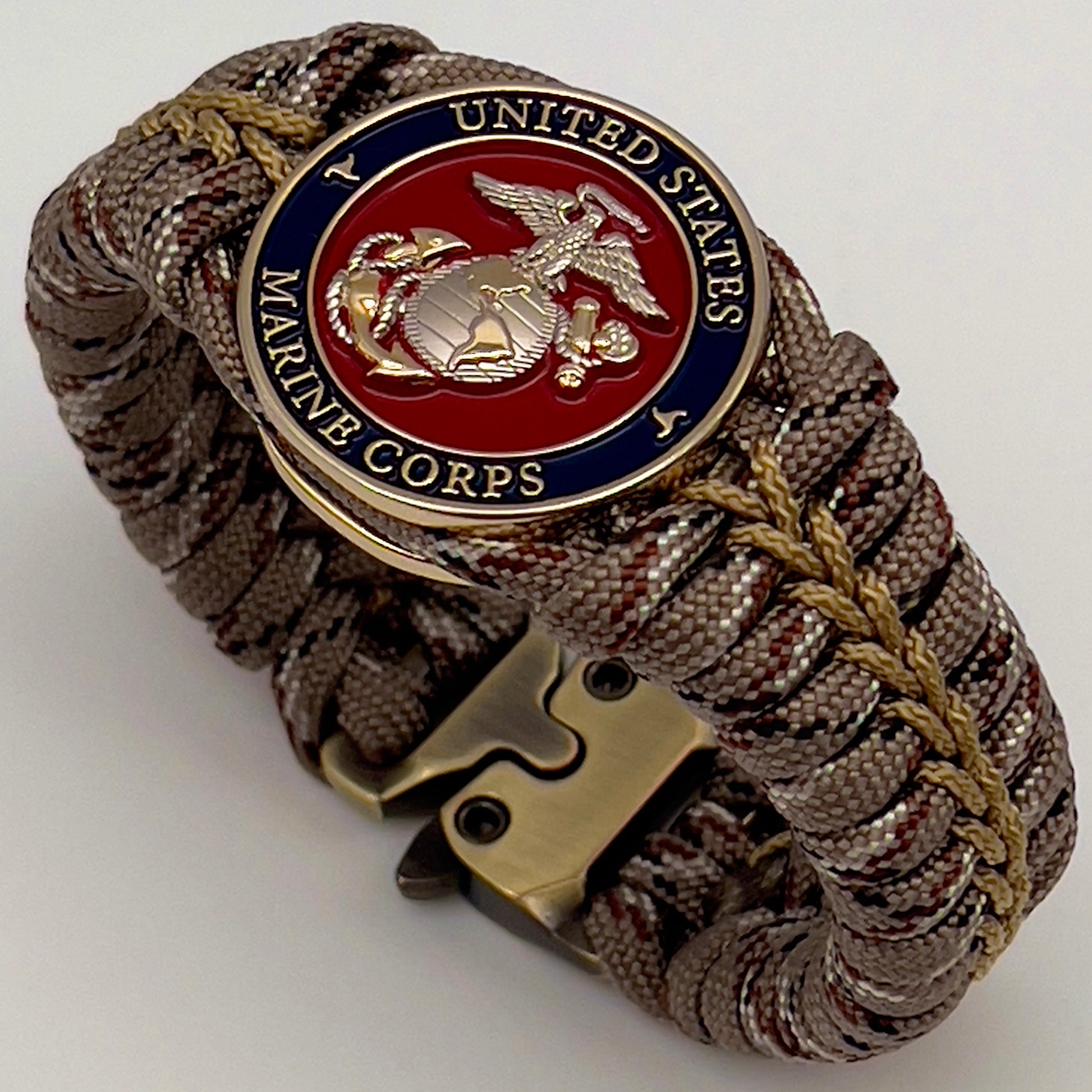 Thick and comfortable braided United States Marine Corps bracelet featuring a 24K gold and silver plated USMC officer Eagle Globe and Anchor medallion, a Cobra style tactical buckle and woven with Desert Camo 550 paracord gold micro cord.