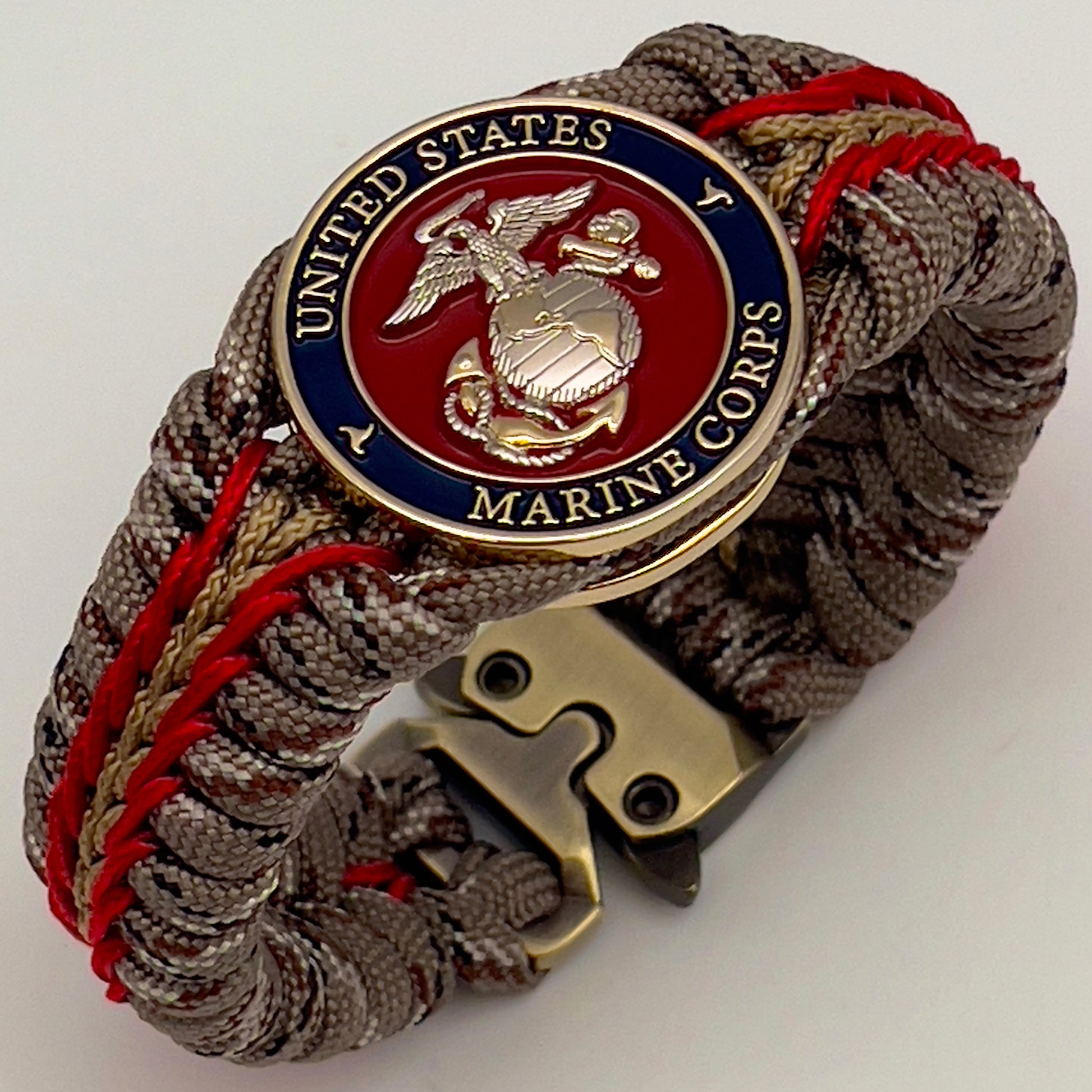 Thick and comfortable braided United States Marine Corps bracelet featuring a 24K gold and silver plated USMC officer Eagle Globe and Anchor medallion, a Cobra style tactical buckle and woven with Desert Camo 550 paracord and Imperial red and gold micro cord.