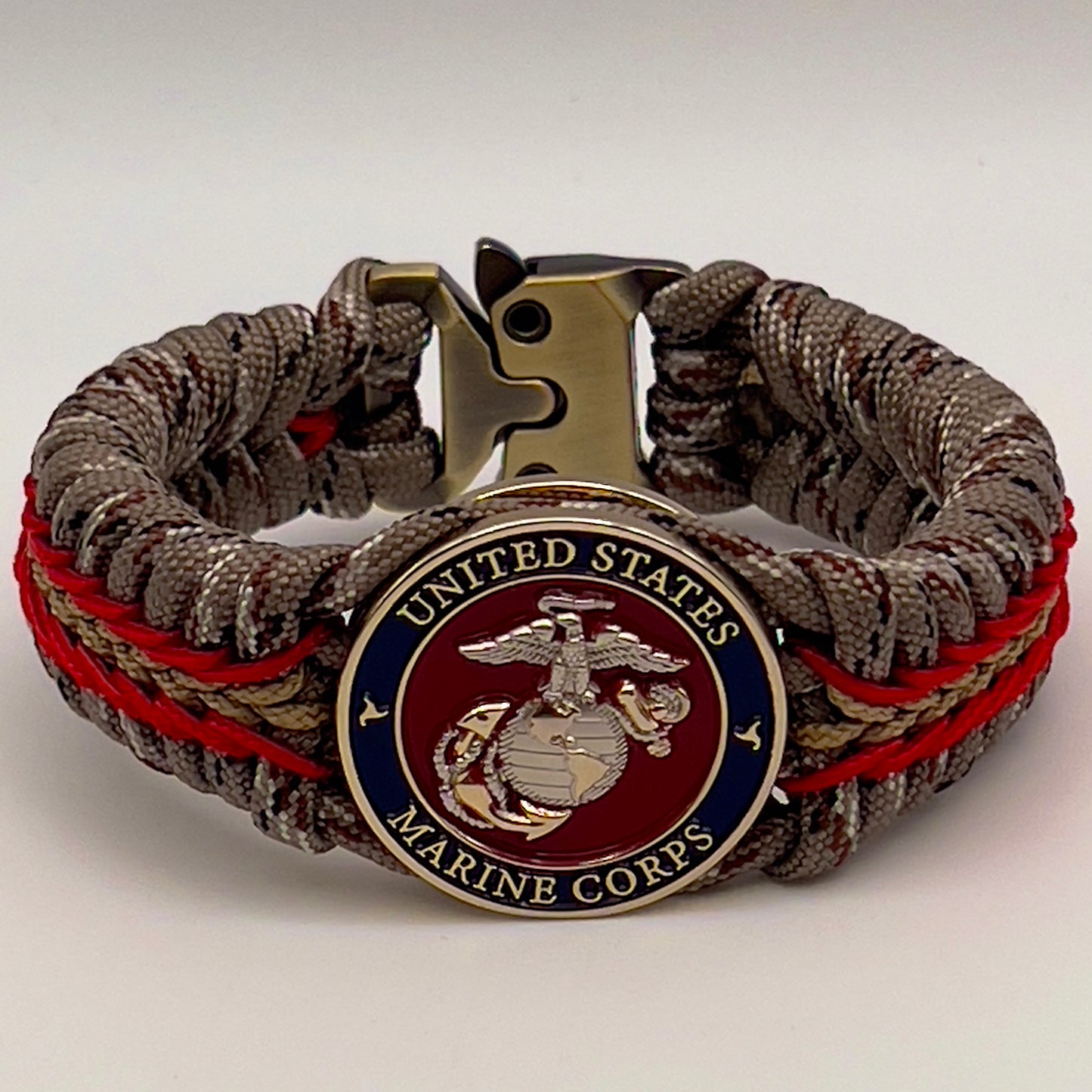 Thick and comfortable braided United States Marine Corps bracelet featuring a 24K gold and silver plated USMC officer Eagle Globe and Anchor medallion, a Cobra style tactical buckle and woven with Desert Camo 550 paracord and Imperial red and gold micro cord.