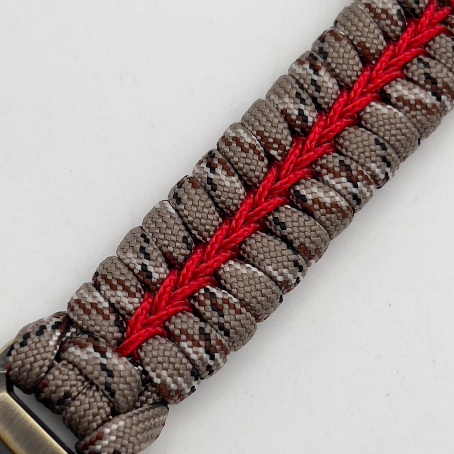 Thick and comfortable braided United States Marine Corps bracelet featuring a 24K gold and silver plated USMC officer Eagle Globe and Anchor medallion, a Cobra style tactical buckle and woven with Desert Camo 550 paracord and Imperial red micro cord.