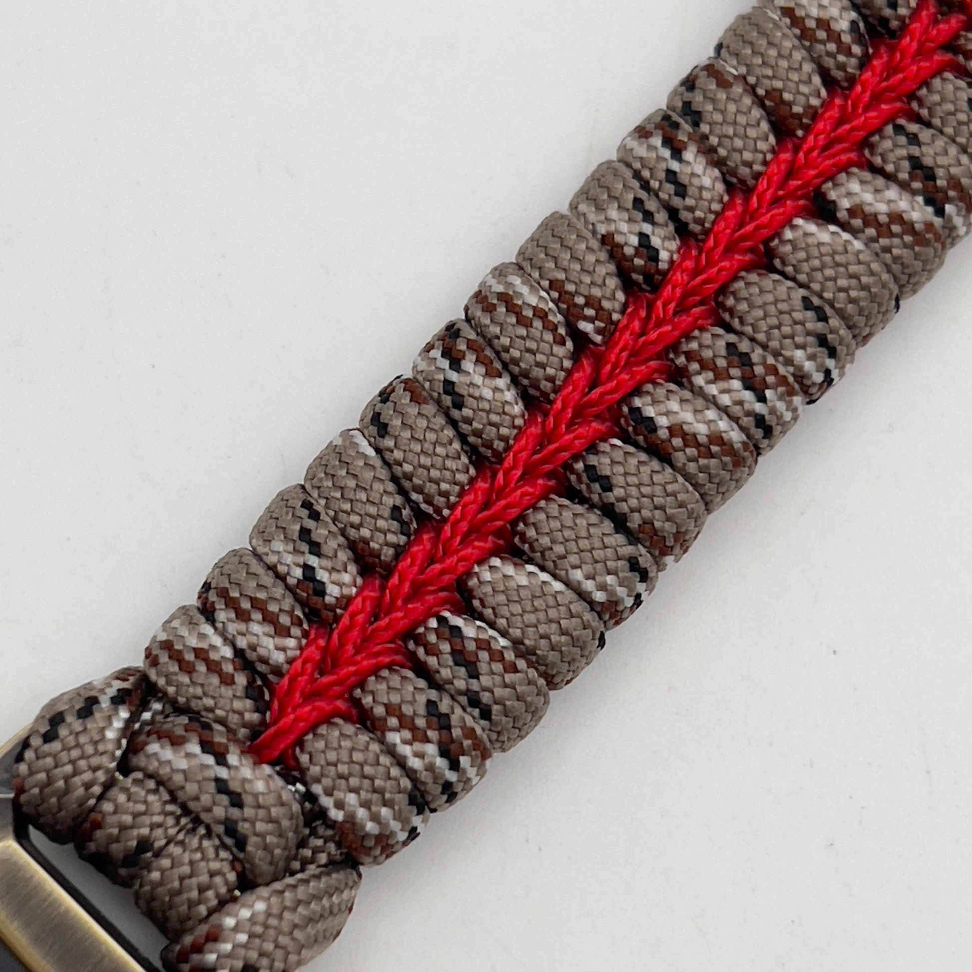Thick and comfortable braided United States Marine Corps bracelet featuring a 24K gold and silver plated USMC officer Eagle Globe and Anchor medallion, a Cobra style tactical buckle and woven with Desert Camo 550 paracord and Imperial red micro cord.