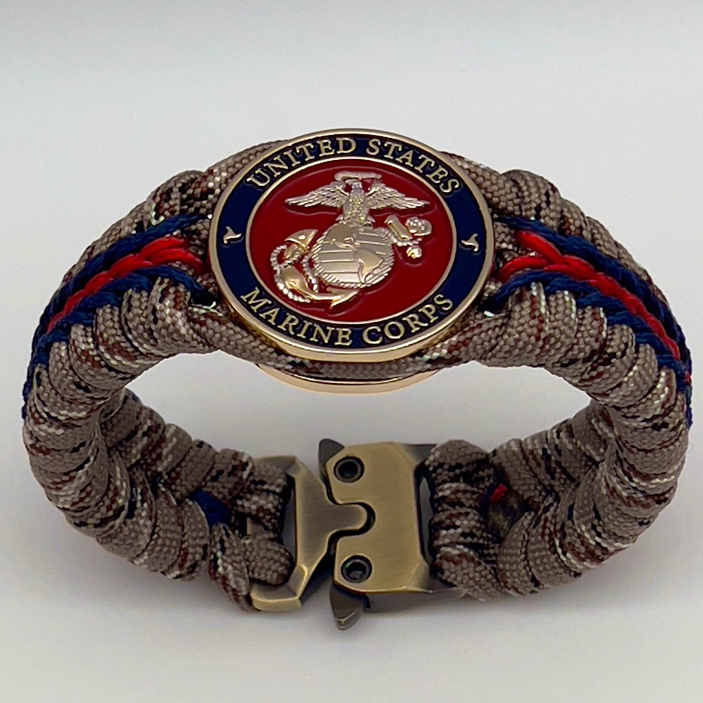 Thick and comfortable braided United States Marine Corps bracelet featuring a 24K gold and silver plated USMC officer Eagle Globe and Anchor medallion, a Cobra style tactical buckle and woven with Desert Camo 550 paracord and Imperial red and Navy Blue micro cord.