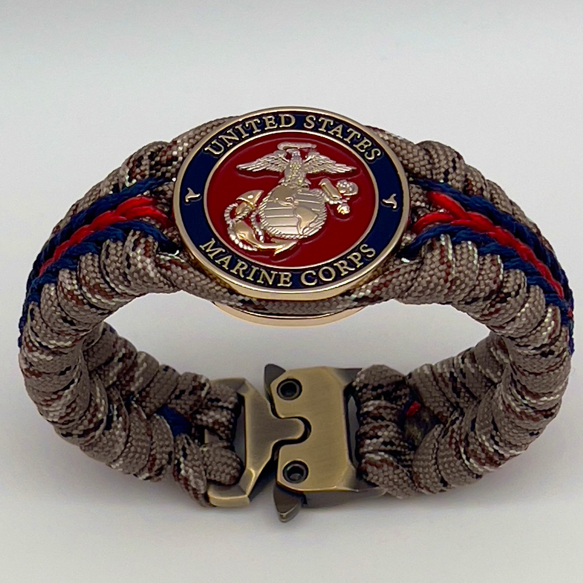 Thick and comfortable braided United States Marine Corps bracelet featuring a 24K gold and silver plated USMC officer Eagle Globe and Anchor medallion, a Cobra style tactical buckle and woven with Desert Camo 550 paracord and Imperial red and Navy Blue micro cord.