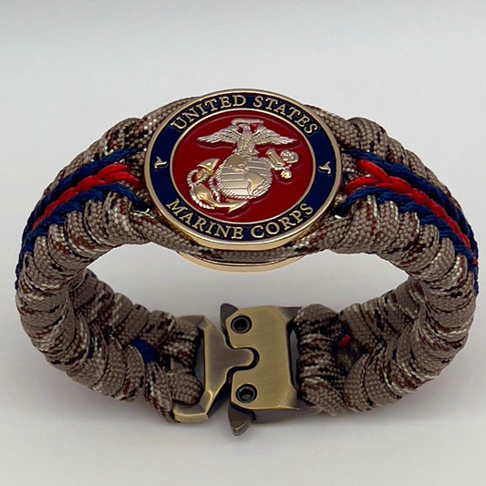 Thick and comfortable braided United States Marine Corps bracelet featuring a 24K gold and silver plated USMC officer Eagle Globe and Anchor medallion, a Cobra style tactical buckle and woven with Desert Camo 550 paracord and Imperial red and Navy Blue micro cord.