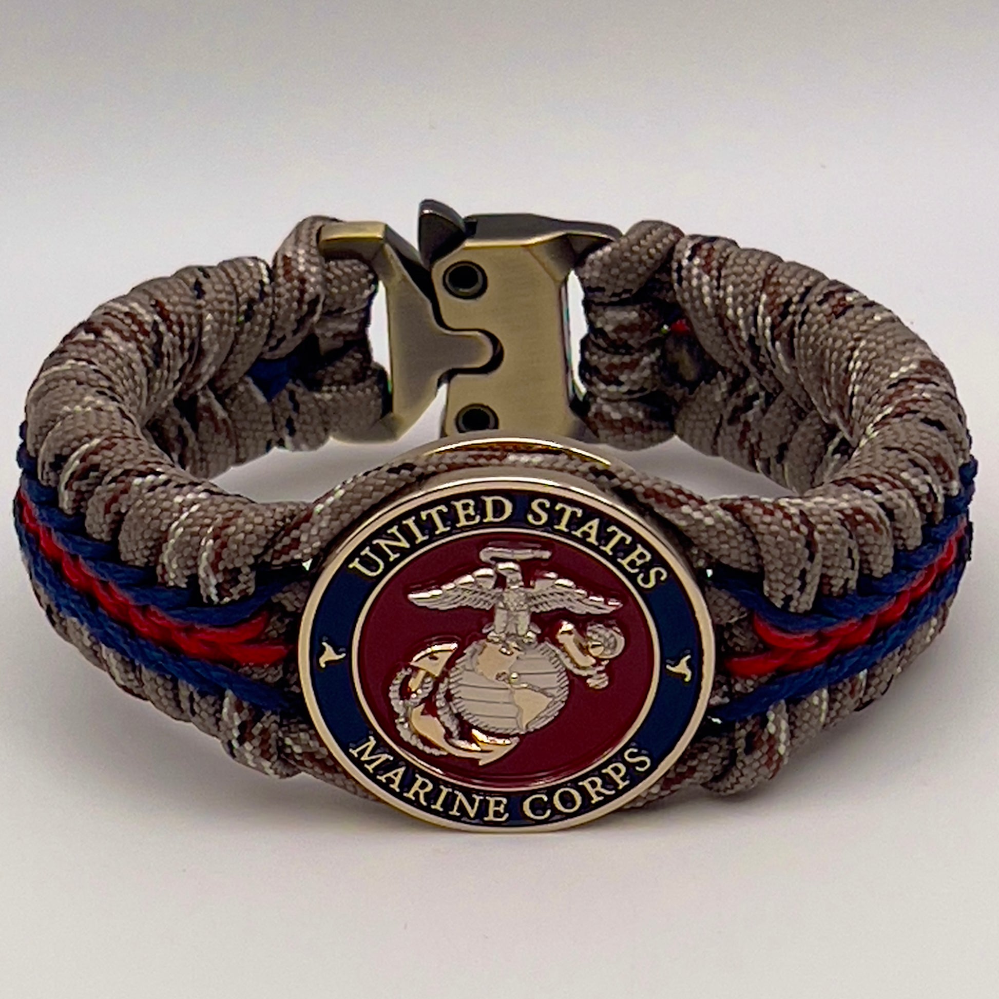 Thick and comfortable braided United States Marine Corps bracelet featuring a 24K gold and silver plated USMC officer Eagle Globe and Anchor medallion, a Cobra style tactical buckle and woven with Desert Camo 550 paracord and Imperial red and Navy Blue micro cord.