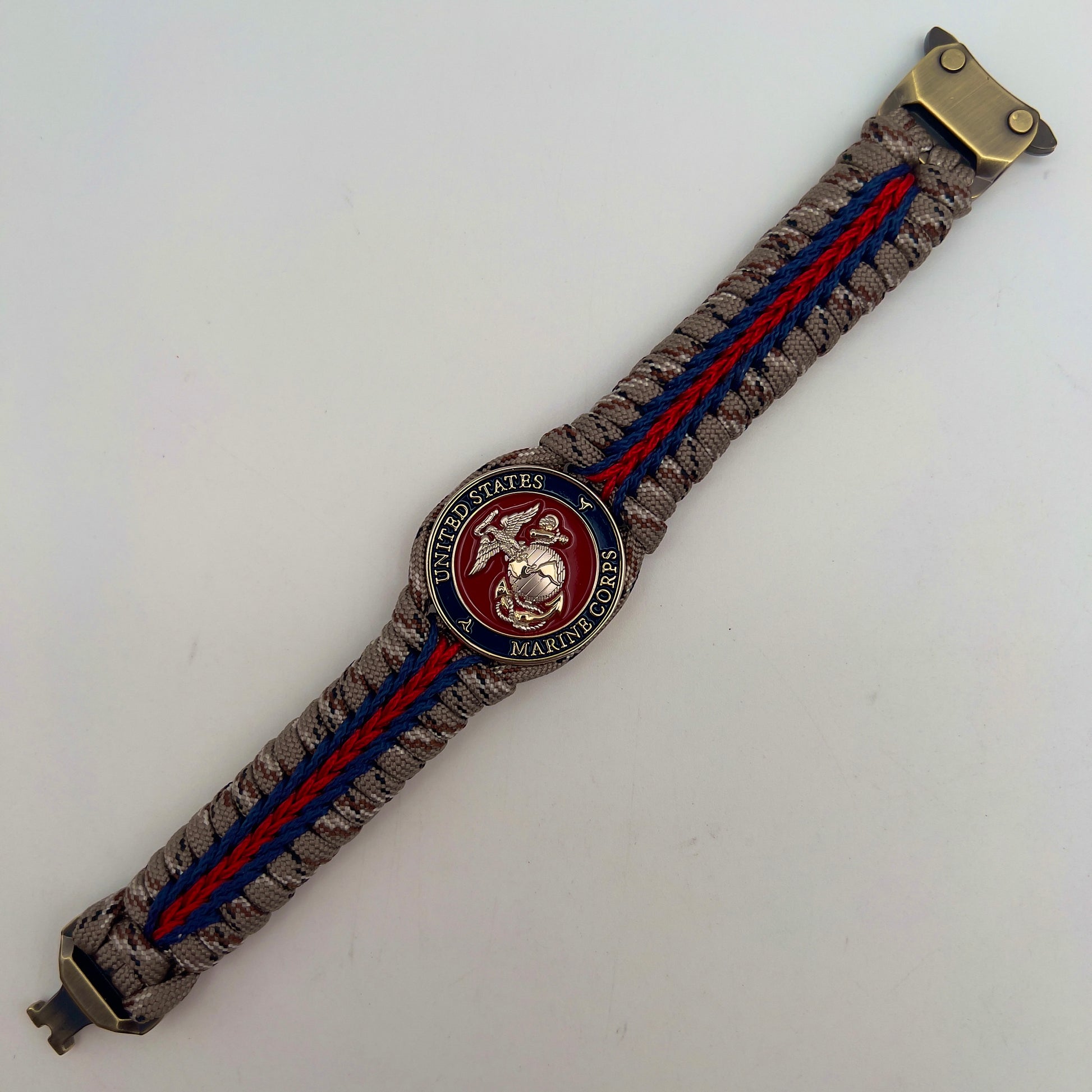 Thick and comfortable braided United States Marine Corps bracelet featuring a 24K gold and silver plated USMC officer Eagle Globe and Anchor medallion, a Cobra style tactical buckle and woven with Desert Camo 550 paracord and Imperial red and Navy Blue micro cord.