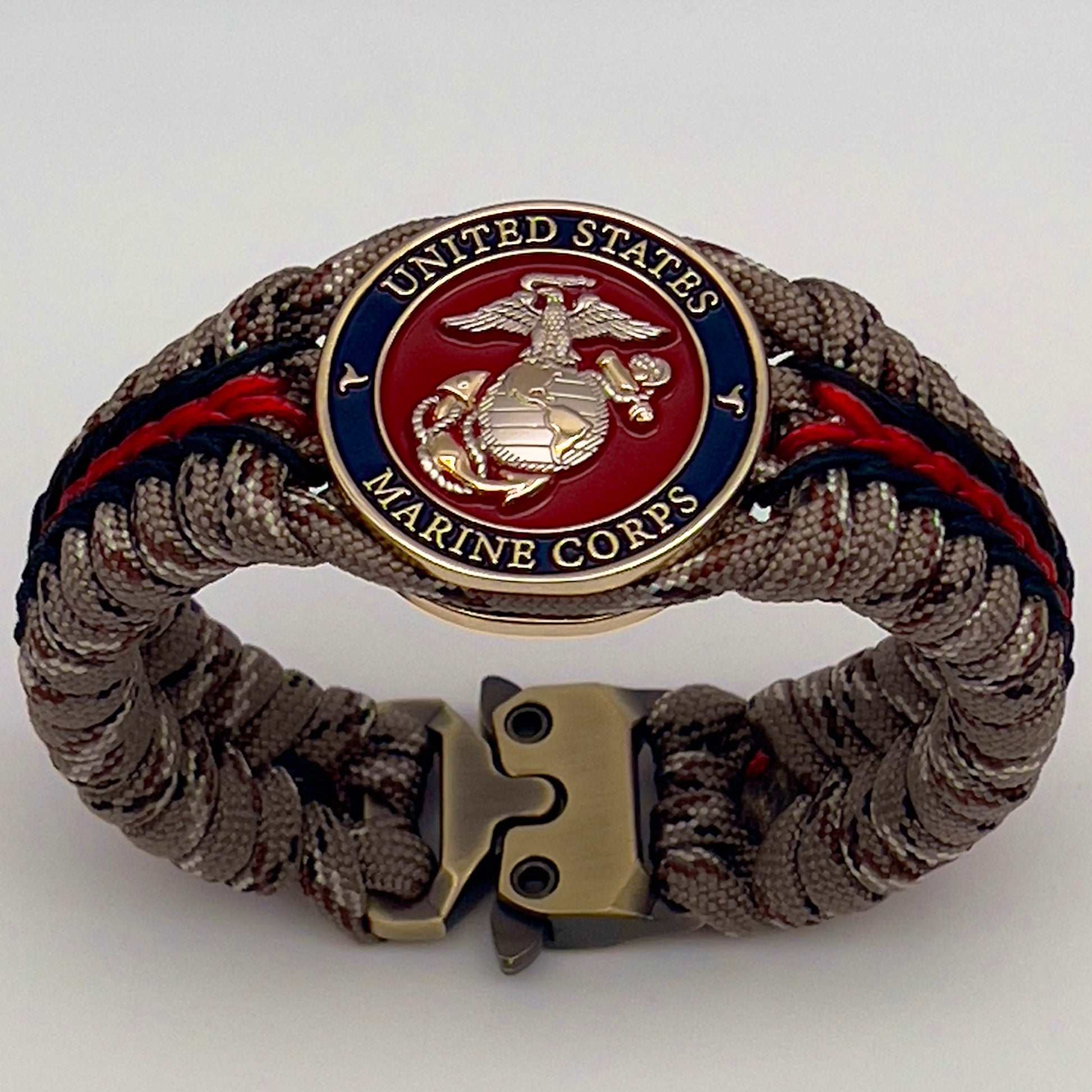 Thick and comfortable braided United States Marine Corps bracelet featuring a 24K gold and silver plated USMC officer Eagle Globe and Anchor medallion, a Cobra style tactical buckle and woven with Desert Camo 550 paracord and Imperial red and black micro cord.